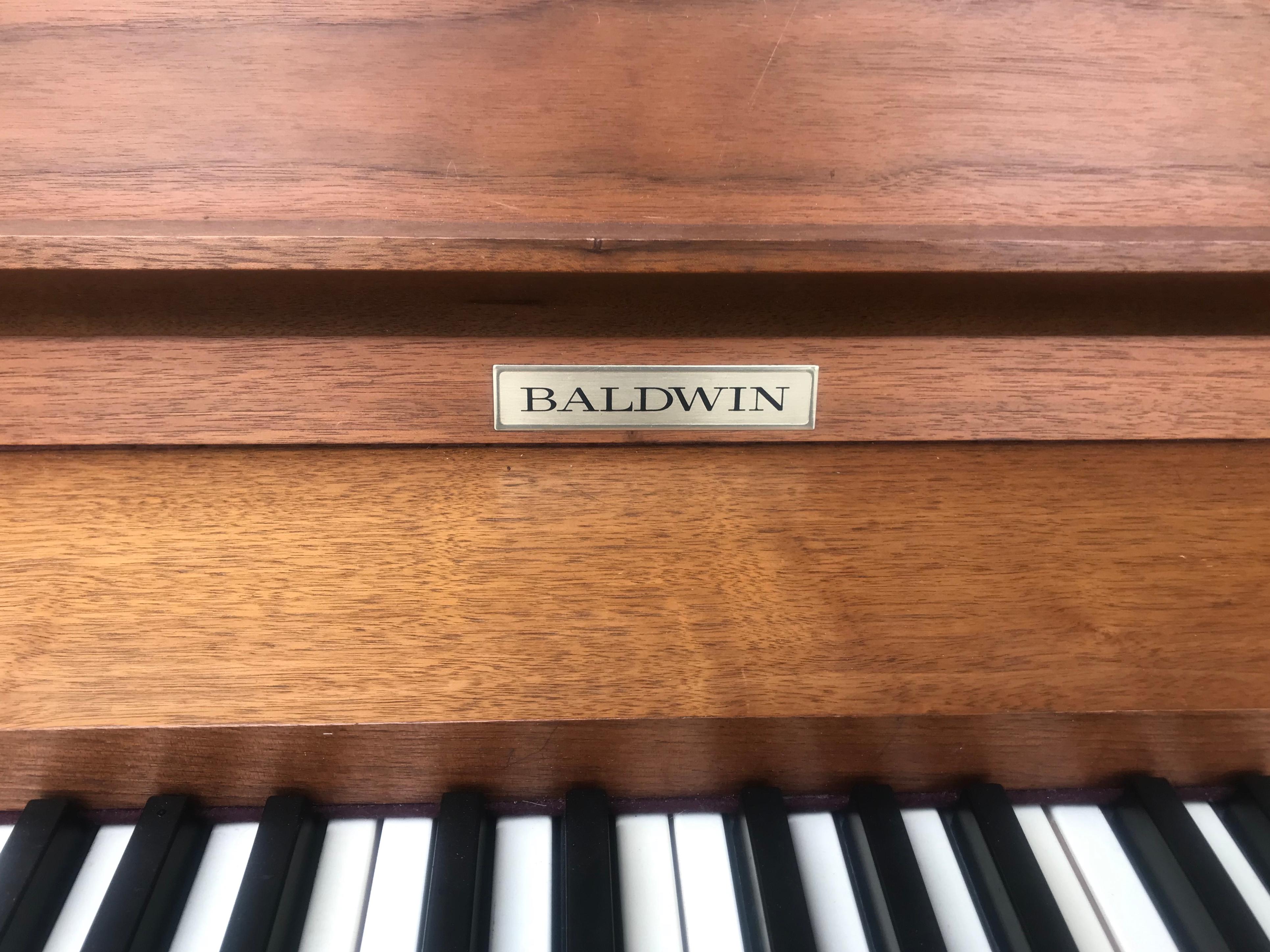 Gorgeous Mid-Century Modern Baldwin Acrosonic spinet piano, note the dramatic angled legs and striking wood grain. The back side of the piano is fully finished with walnut and caned panels so it can be placed anywhere in a room, small in size, big