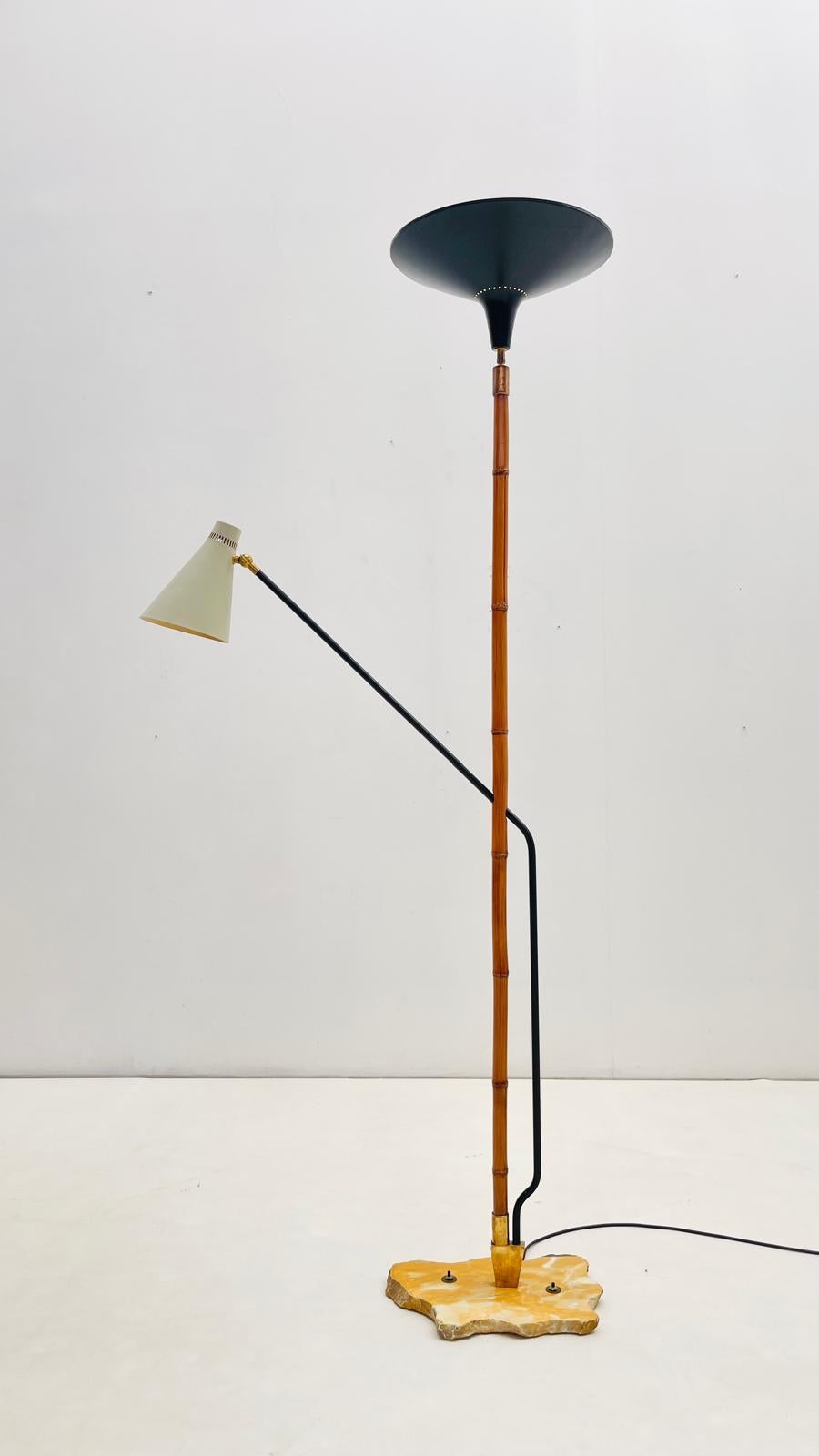 A floor lamp combining natural and industrial materials. The central stem is made from bamboo, set into an irregularly shaped marble base. A black uplighter shade sits at the top, while a secondary arm holds a pale conical reading light. Brass