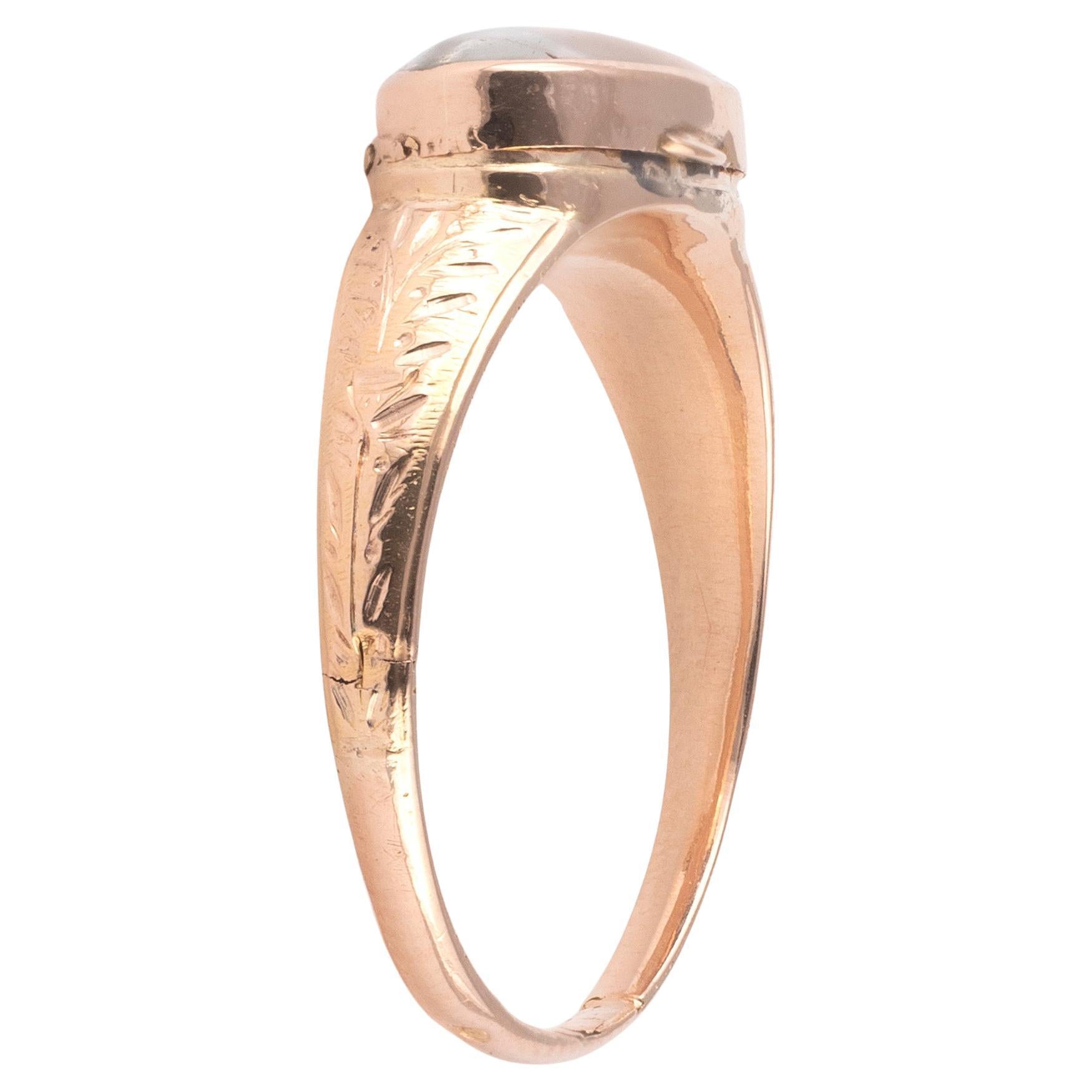 The top of the ring presents an oval shaped rock crystal, cabochon, revealing the interior compartment, likely intended for holding a relic or protective amulet., to a chased with foliage surrounding shoulders, mounted in gold.
As a typical design