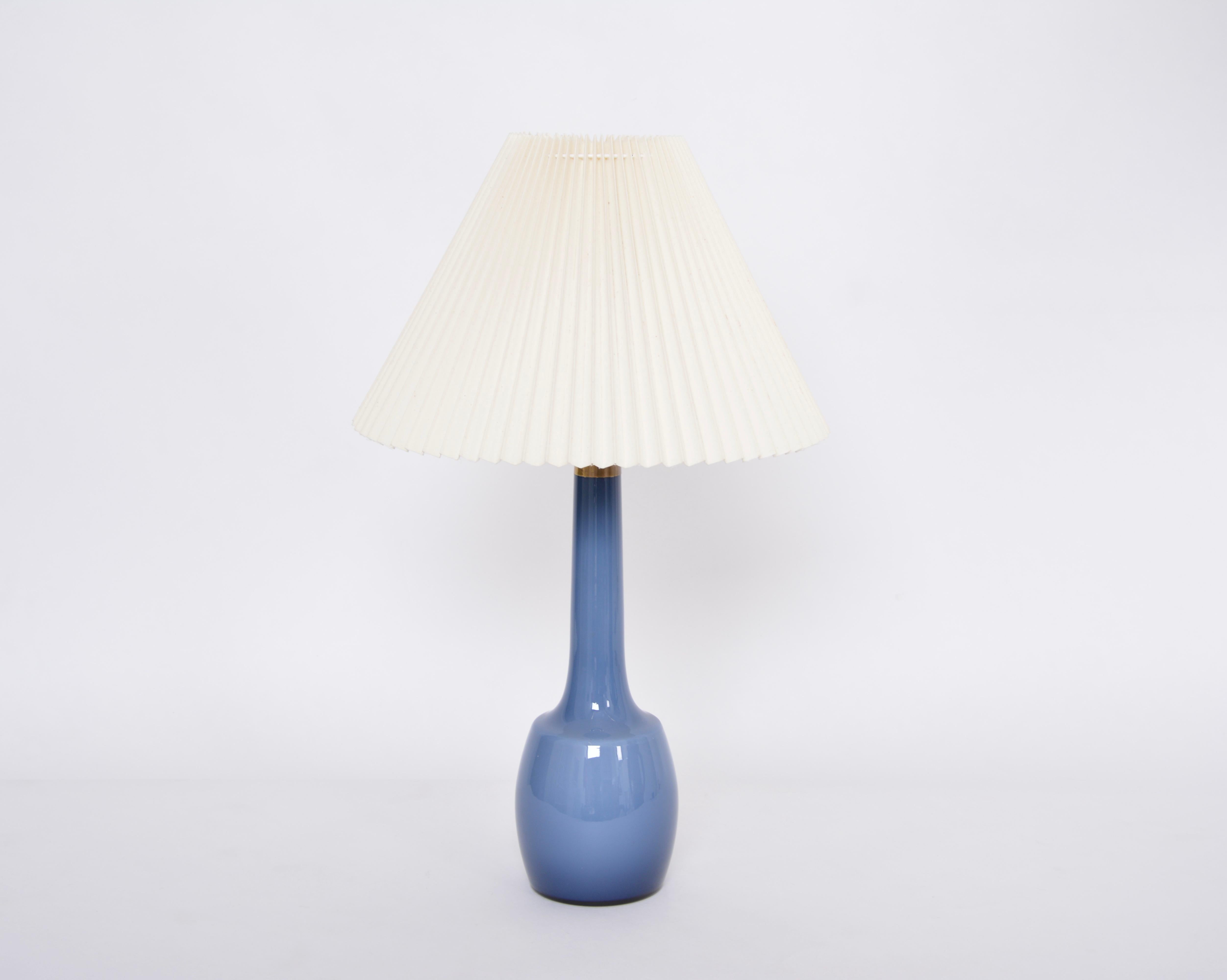 Rare blue Danish midcentury table lamp by Esben Klint for Holmegaard
This lamp was designed by Esben Klint in the 1950s and produced by Kastrup Holmegaard Fyns Glasværk. The lamp is made of glass and features a brass top. The lamp has the original