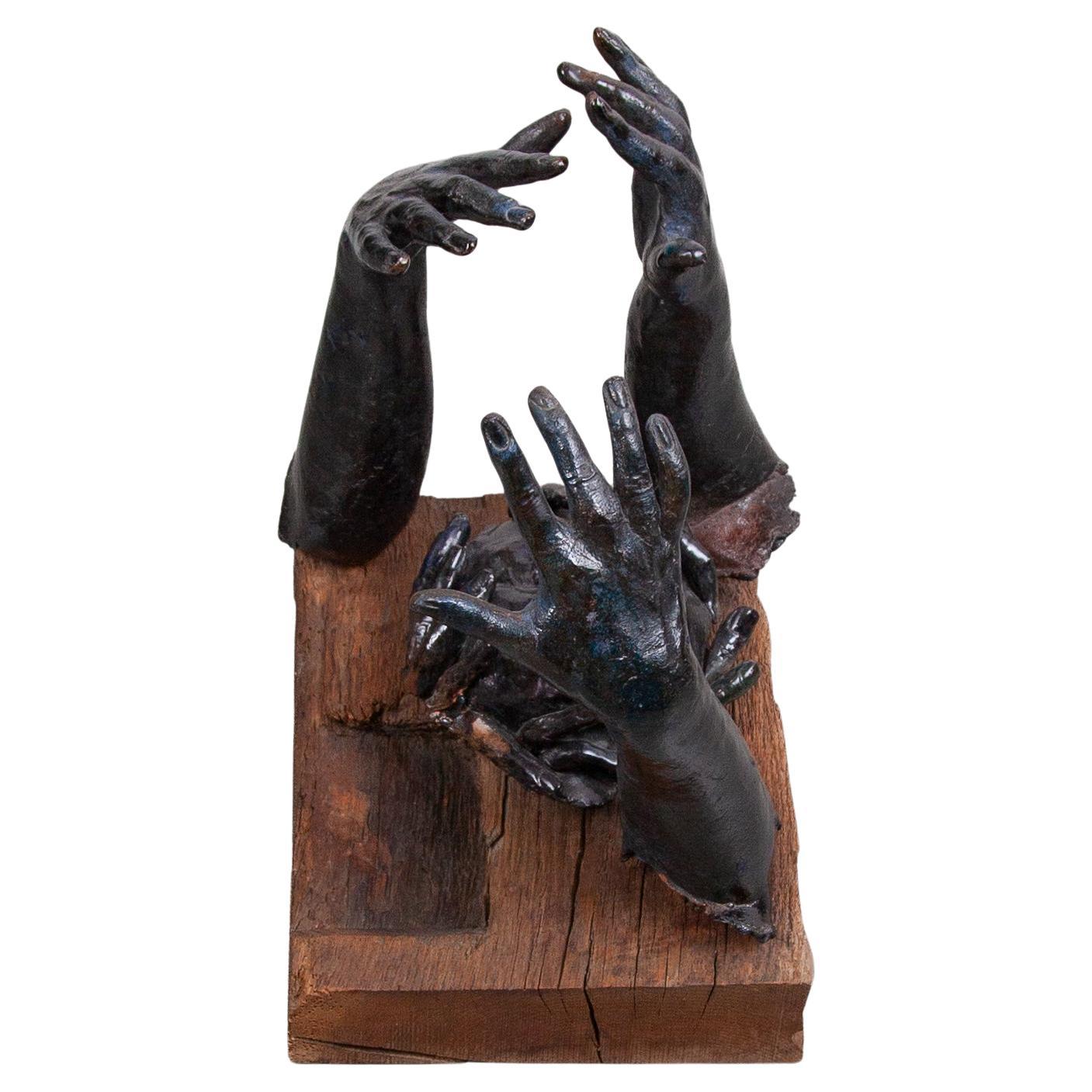 A beautiful sculpture featured with three well formed hands around a face connected at the wooden statue in deep blue glaze with nuances to the green. The handcrafted sculpture is from the 1970s and designed by an unknown artist, Belgium.