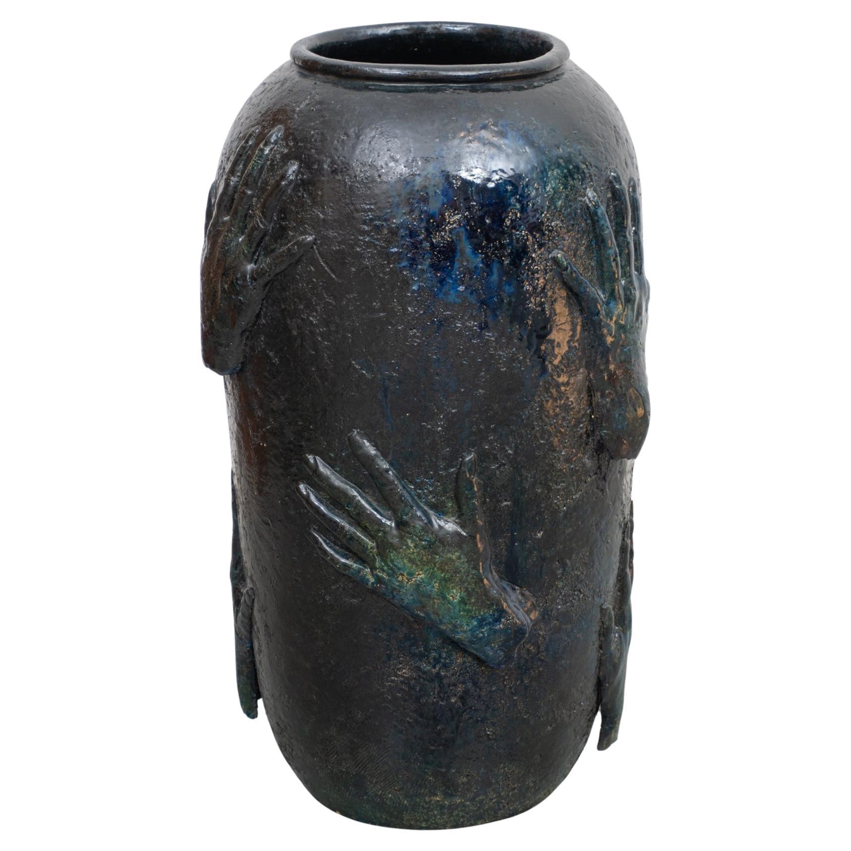 Un beau grand vase en céramique à la glaçure bleu profond avec des nuances de vert, décoré de différentes mains embrassant le vase dans diverses positions. Le vase date des années 1970 et a été conçu par un artiste inconnu, Belgique.