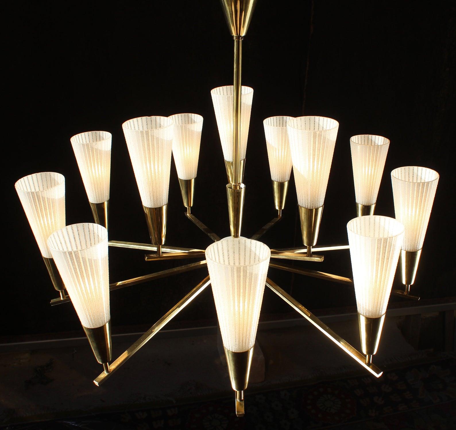 12-light chandelier, 1960, Stilnovo type

Polished brass and moulded conus glass blossoms

This fine Italian brass and glass chandelier is in fine original constitution with fine patina. The 12 (+2 for reserve) filigree moulded and hand-enameled