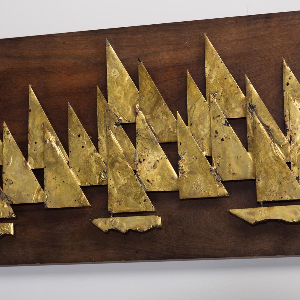 A rare brass metal sailboat wall sculpture by Peter Pepper mounted on a wooden backdrop, 1960s.