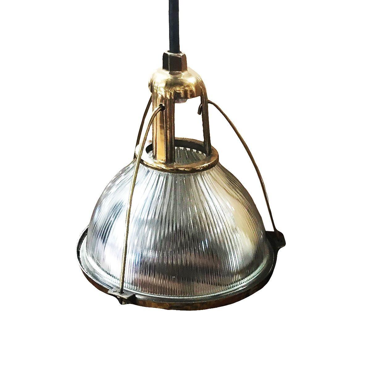 This industrial yet elegant hanging lamp from the 1940s features a Holophane glass shade. These pendant lights are connected by an aluminum casing fixed to the top of the light fixture and are a rare brass-plated variant not seen often.

A holophane