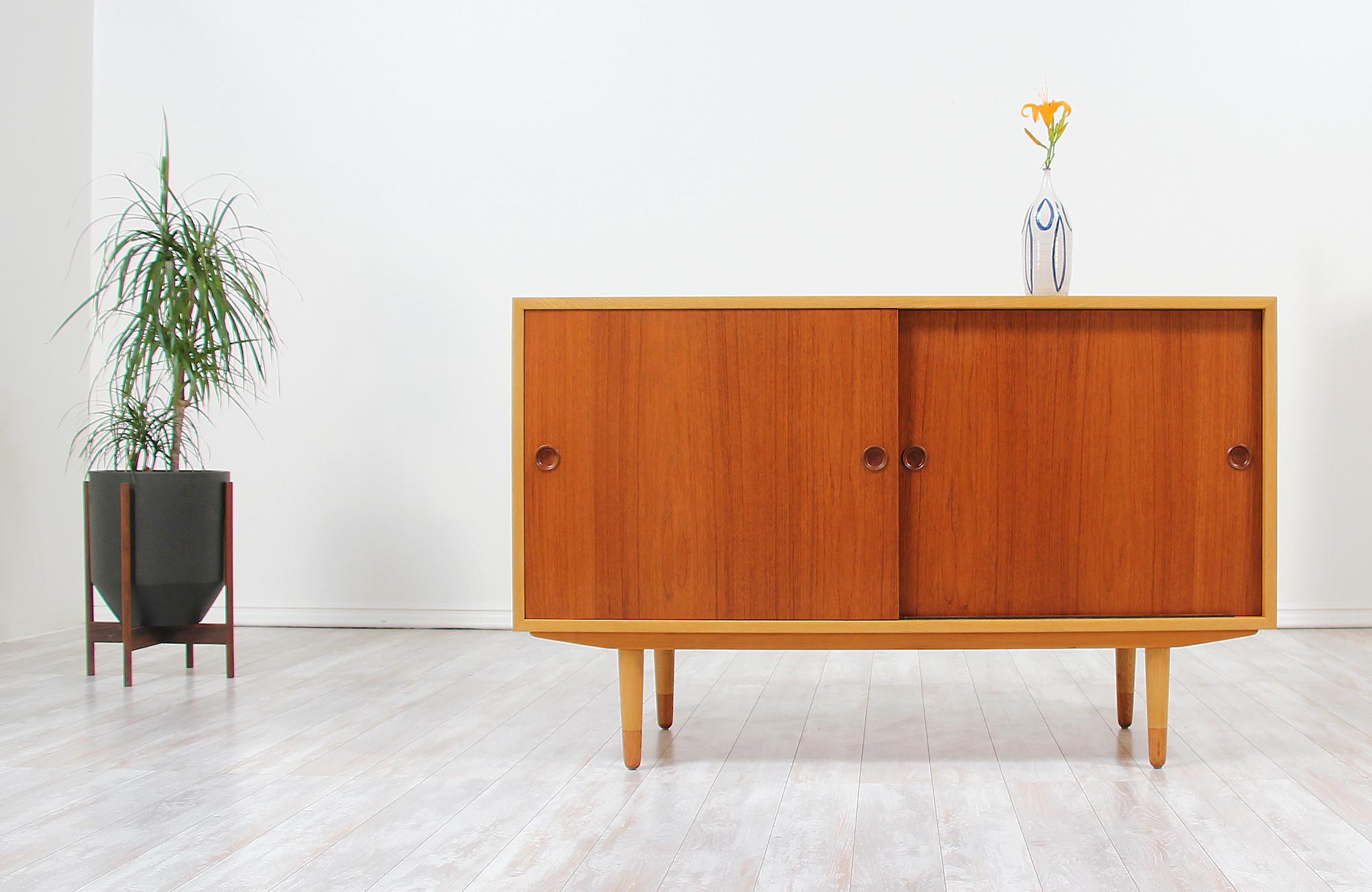 Beautiful modern credenza designed by Børge Mogensen for Søborg Møbler in Denmark, circa 1950s. This elegant multicolored credenza features a sturdy oak wood case and tapered legs with teak wood sliding doors and caps on the legs that create a clean