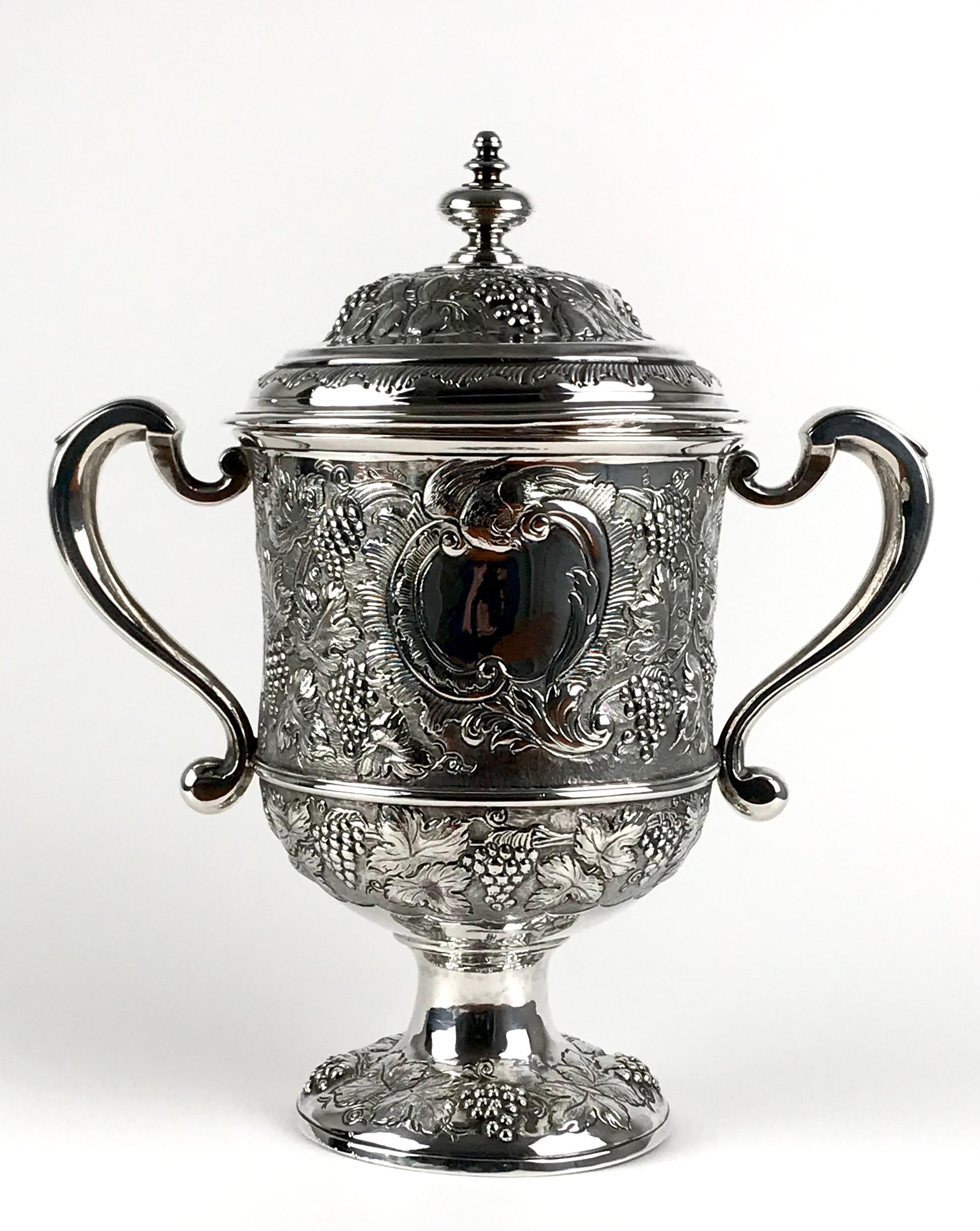 A Rare and Magnificent Queen sterling silver twin handled cup and cover, 
London 1712
Of baluster form upon a circular foot, the twin double C scroll handles.
The body with embossed decoration in high relief of grapes and vive leafs, the centre