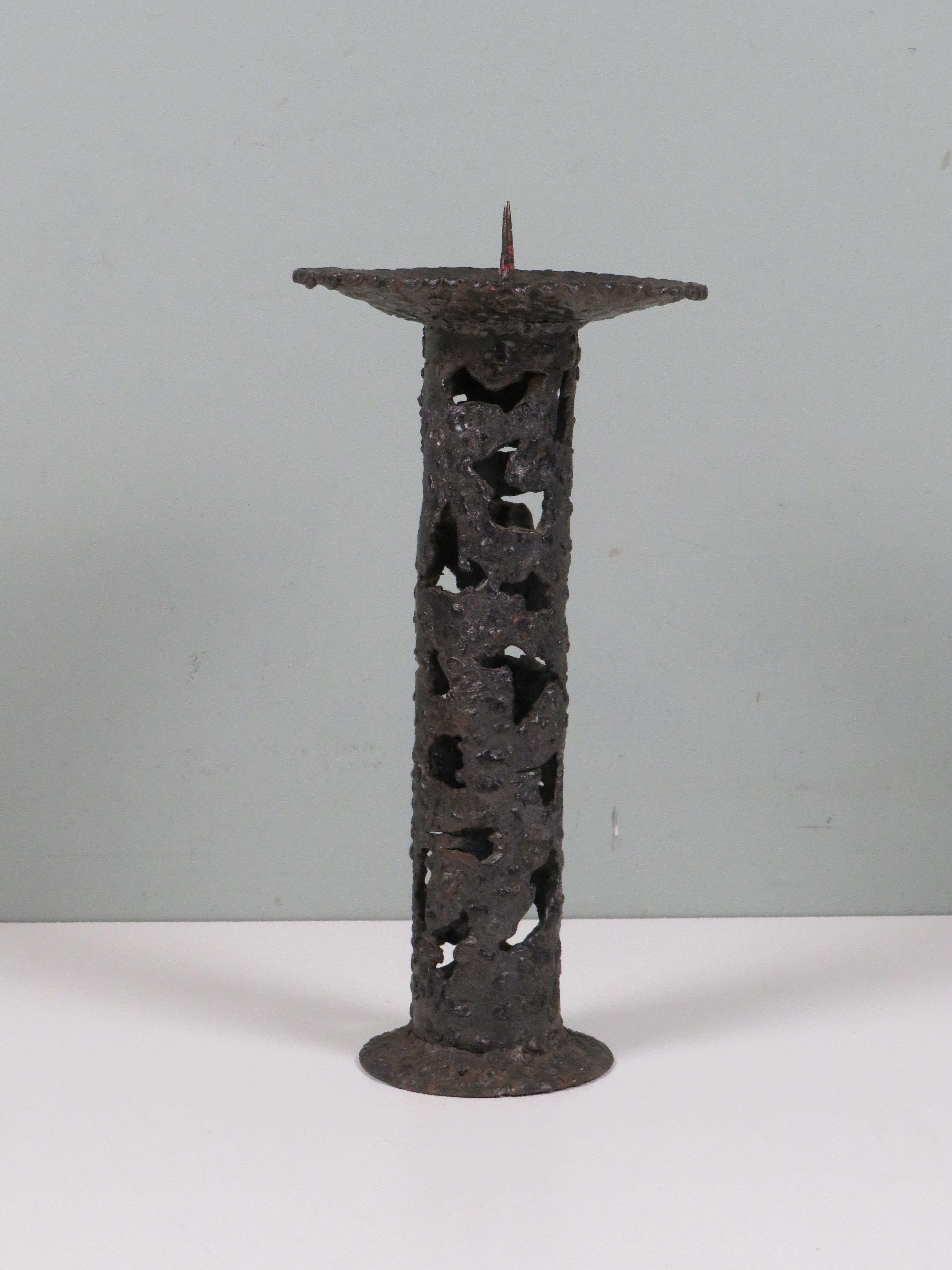 A rare and beautifully executed Brutalist iron candleholder, handcrafted in Europe during the 1960s. The columnar form, pierced with organic voids, and the thick, hammered surface create a dramatic interplay of light and shadow.

Rich in patina and