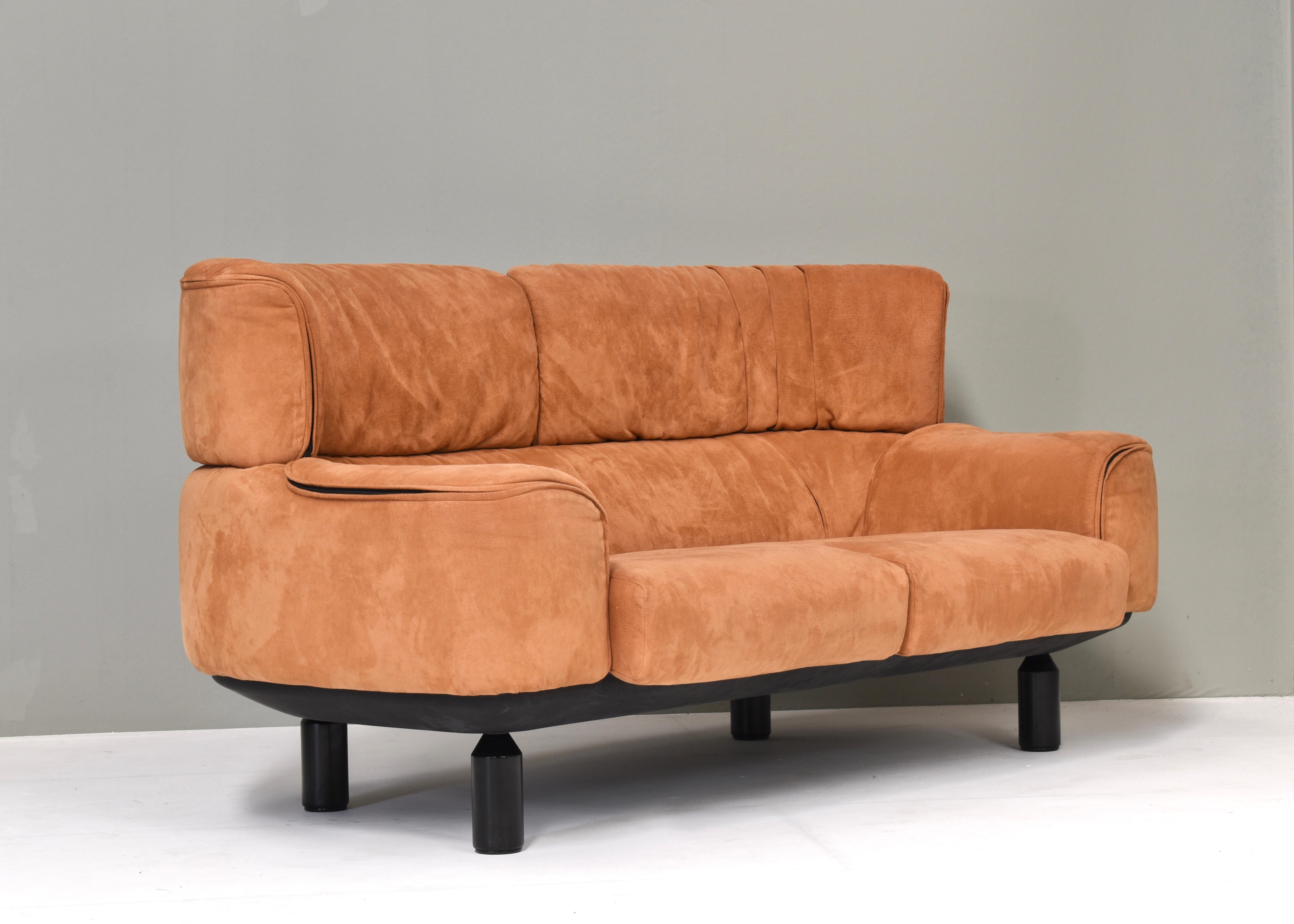 Elegant two-seat loveseat designed by Gianfranco Frattini for Cassina in 1987 and is covered in beautiful terracotta alcantara. The integrated headrests curve around to envelop the sitter. Designed with individually zippered upholstery panels to