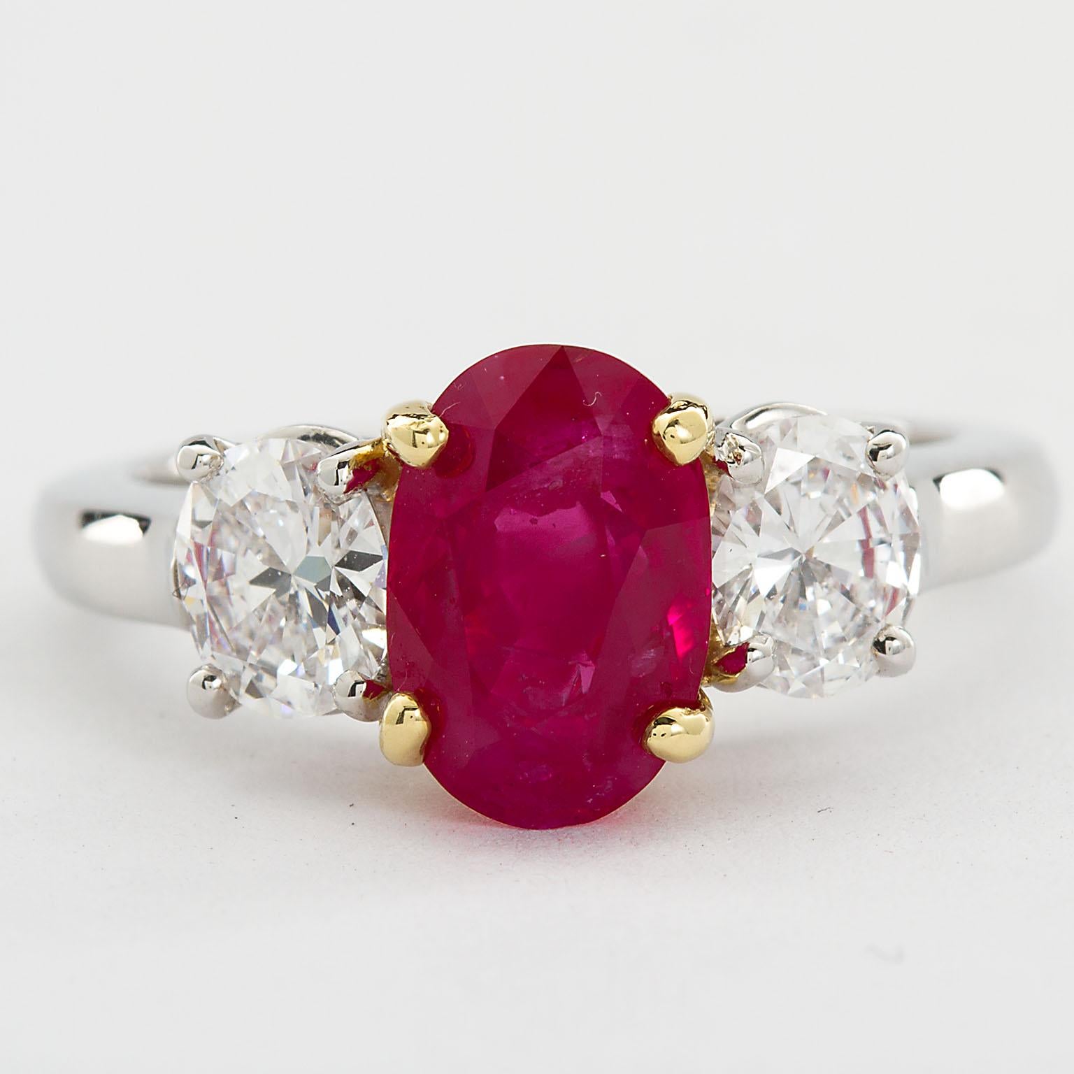 A classic platinum and 18k gold three-stone ring with a rare center Burma no-heat oval shape ruby weighing 2.64 ct, set between two diamond ovals weighing approx. 1.00 carat total. 
Ruby specs (Based on accompanying American Gemological Laboratories