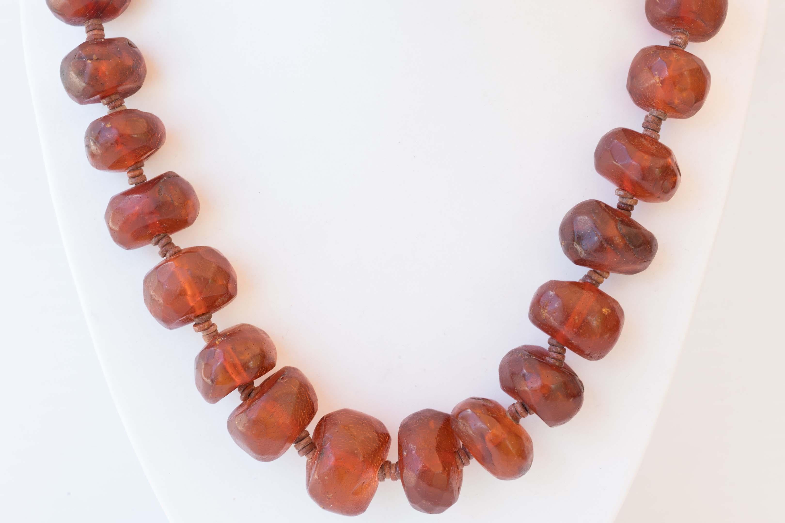 Rare reddish brown Burmite amber fossil tribal necklace late 19th century. Made of 34 irregular facetted beads from 13mm to 24mm and 4 round stone beads in between. The necklace measures 23 1/2 inches long, with signs of wear and minor fading. Made