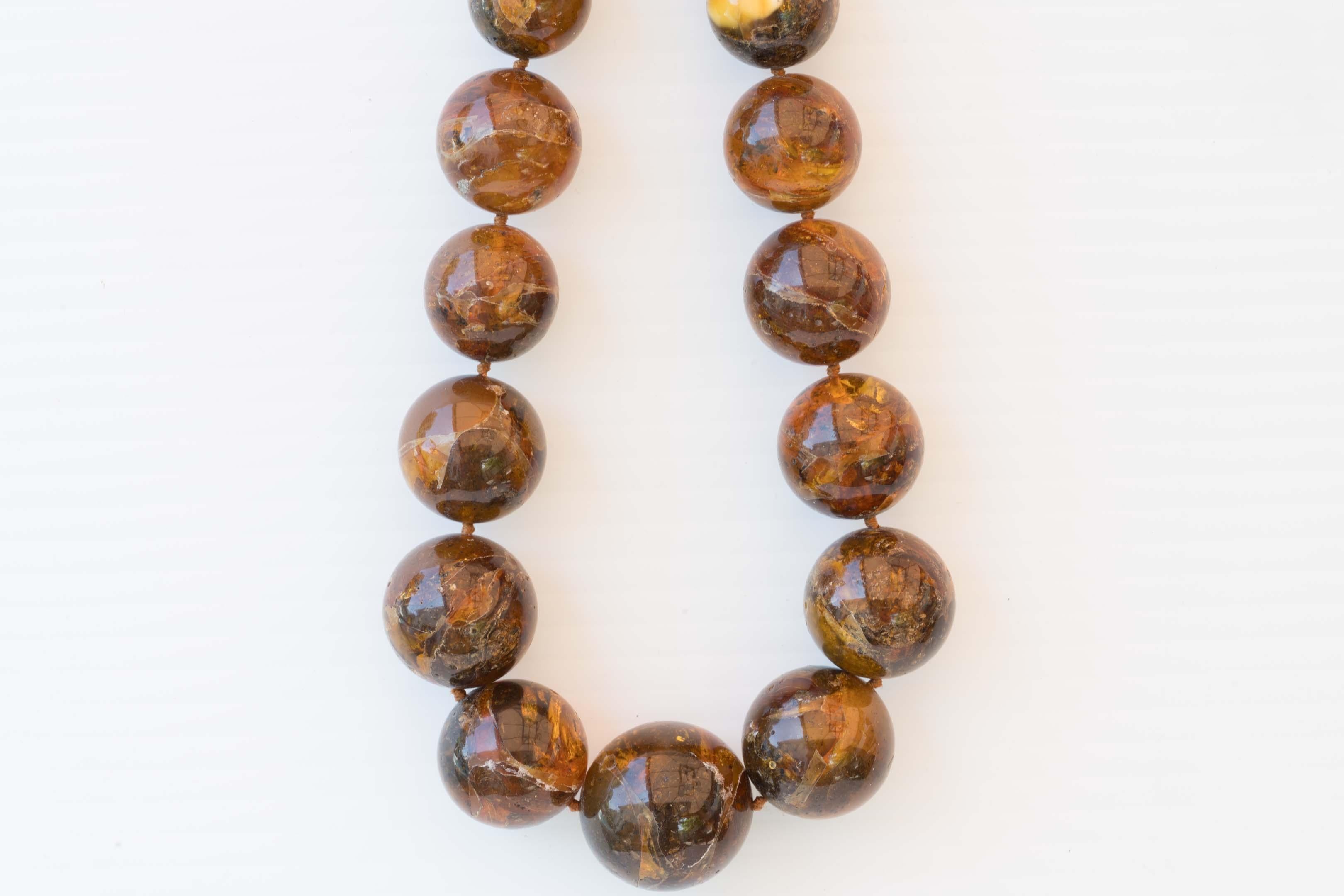 A rare Burmite tribal graduate amber necklace measures 24 inches long with 29 knotted beads measuring 13mm to 27.5 mm in diameter. From clear to reddish and yellow inclusion colour. Signs of wear and natural cracks & imperfections. Made in Burma.