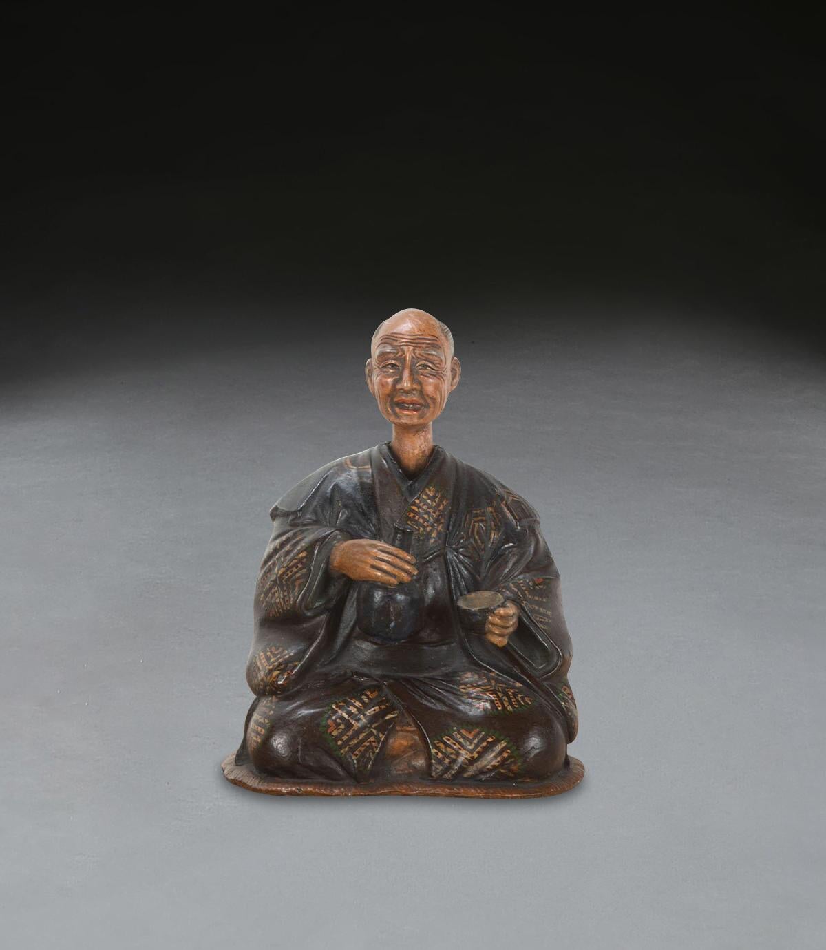 A rare C19th English pottery figure of a seated Japanese gentleman in traditional robes, with a nodding head which is lead weighted inside to make his head rock, with a bottle and cup in his hands. All still retaining its original decoration. Circa