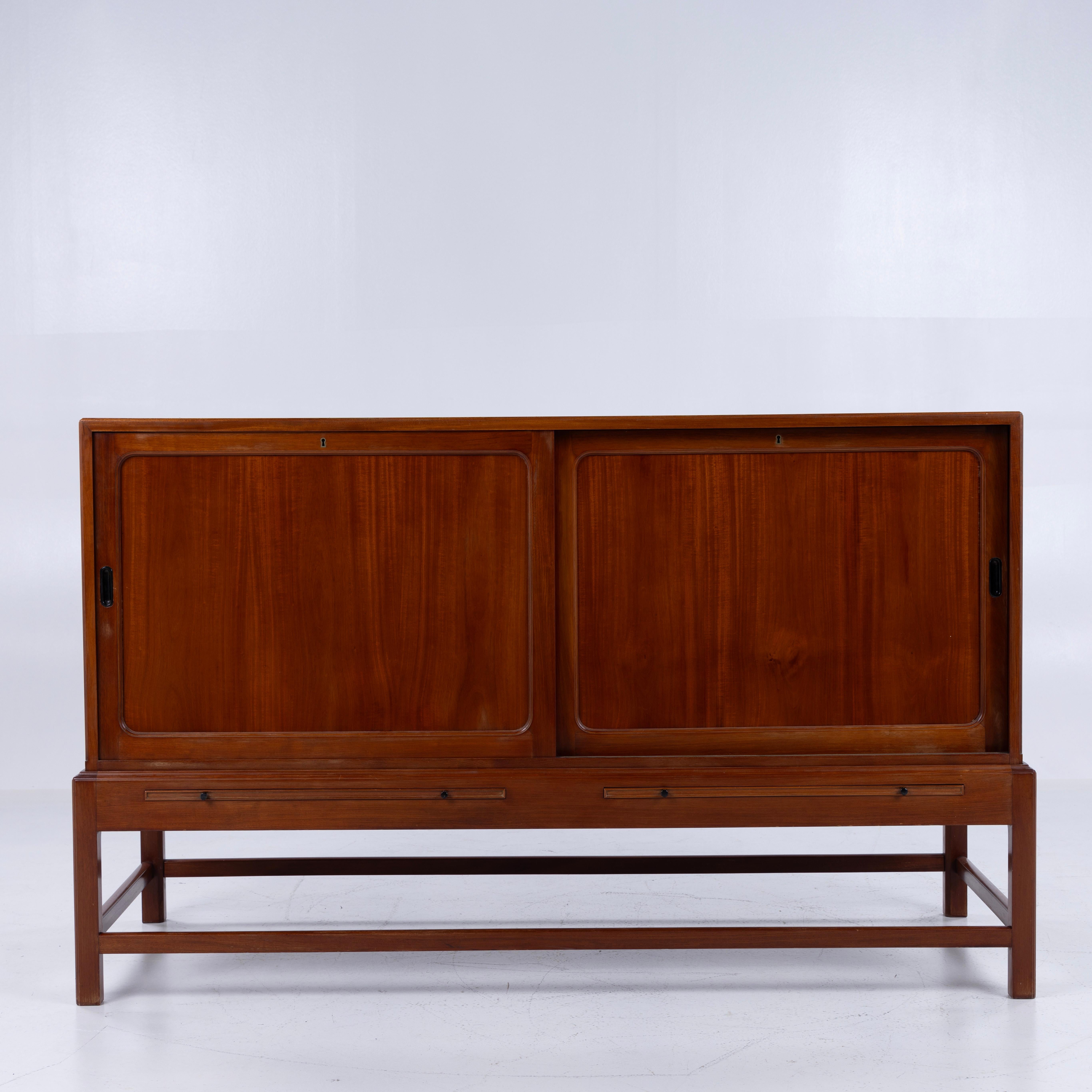 Rare cabinet en acajou avec portes coulissantes. Equipé d'étagères et de tiroirs coulissants. Poignées en laiton de chaque côté. Marqué du fabricant Rud Rasmussen et conçu par Kaare Klint.