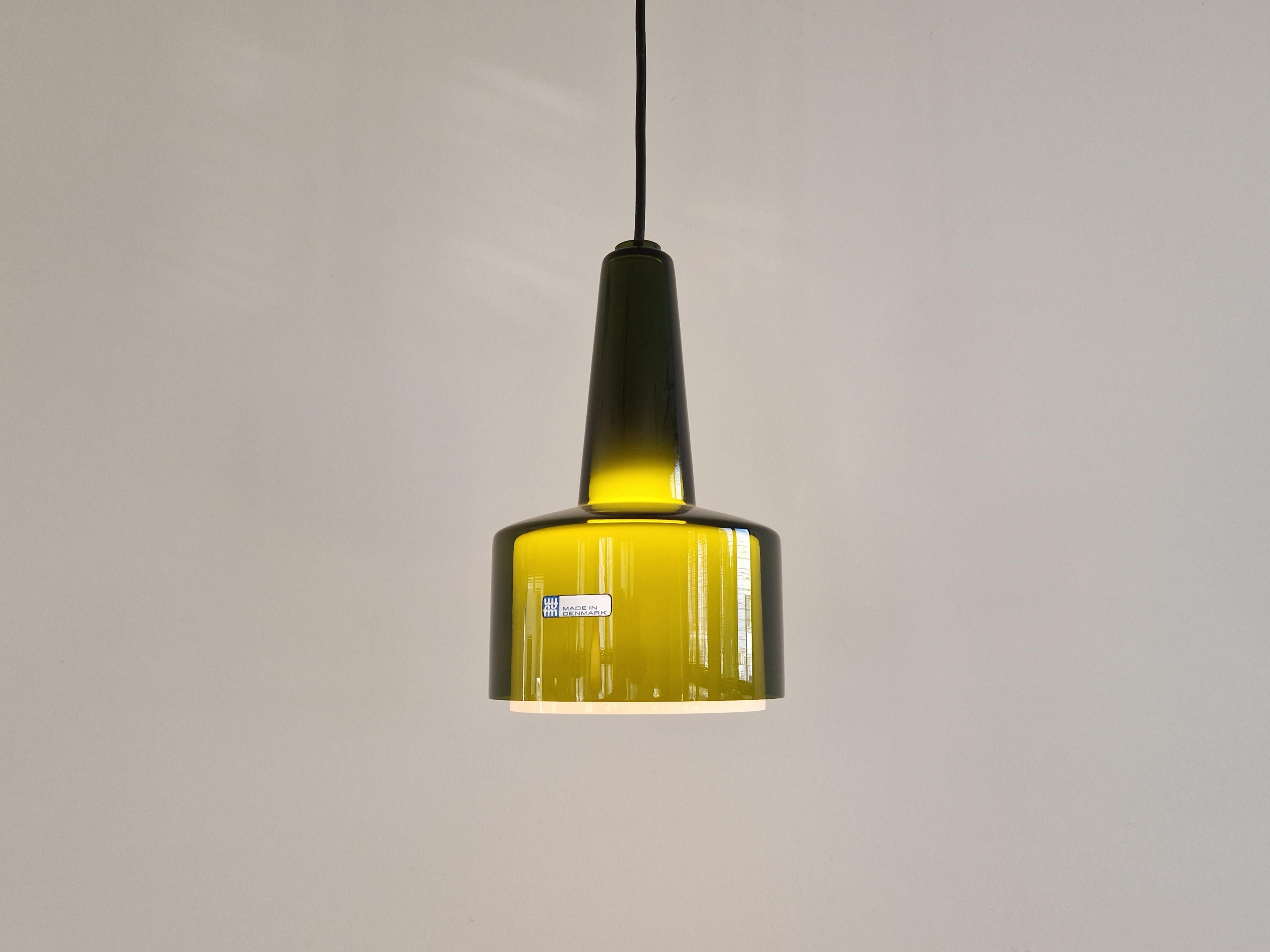 This beautiful and elegant pendant lamp, model 'Capri' was designed and made for Fog & Mørup in Denmark in the 1960's. It has a clear olive green glass exterior shade and a smaller opaline white interior shade that just comes out underneath the