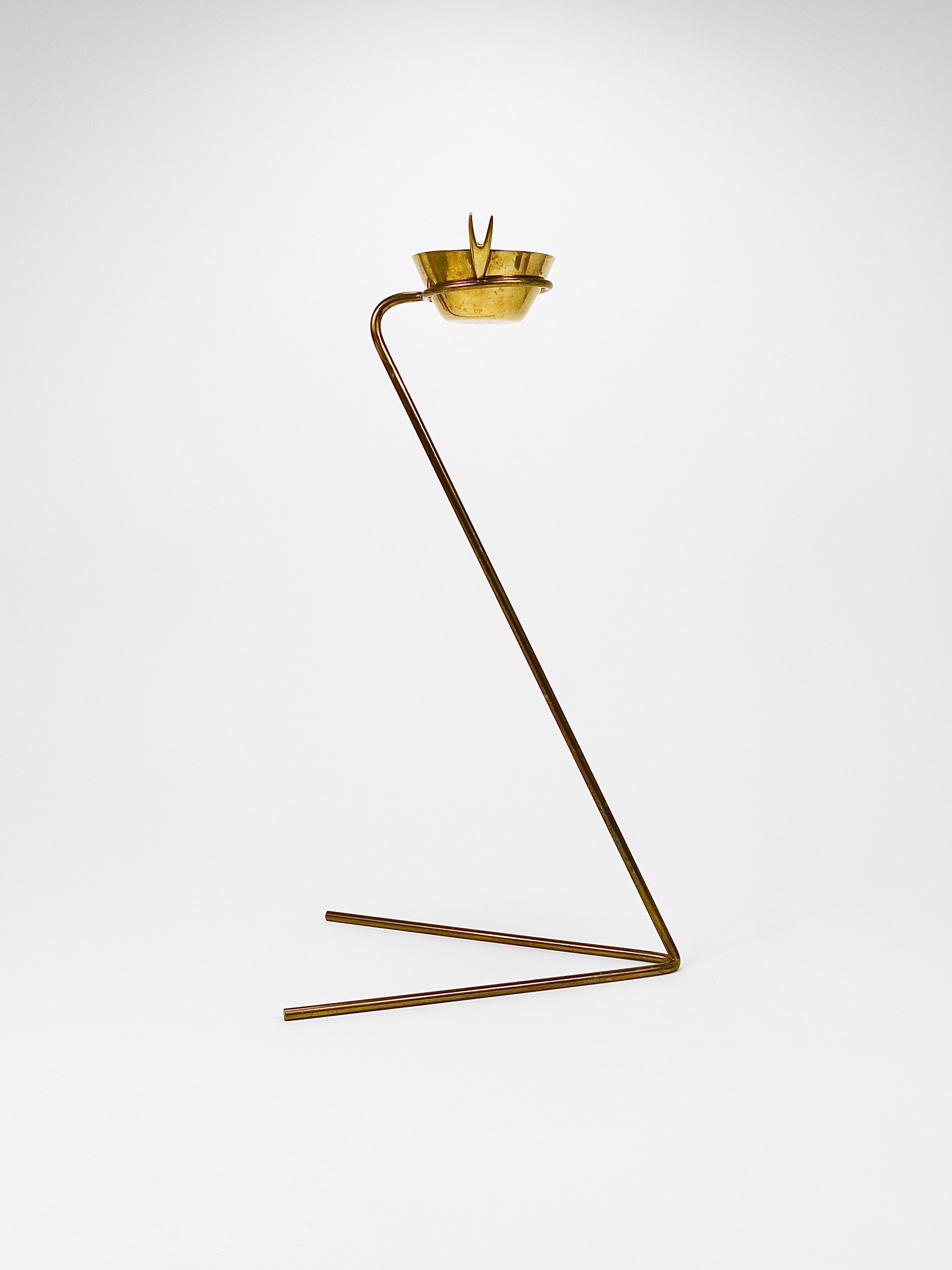 A beautiful vintage and authentic minimalist standing ashtray from the 1950s, designed and crafted by Werkstätte Carl Auböck in Vienna, Austria. This sculptural piece features a triangular brass base and a removable brass ashtray bowl. It is in very