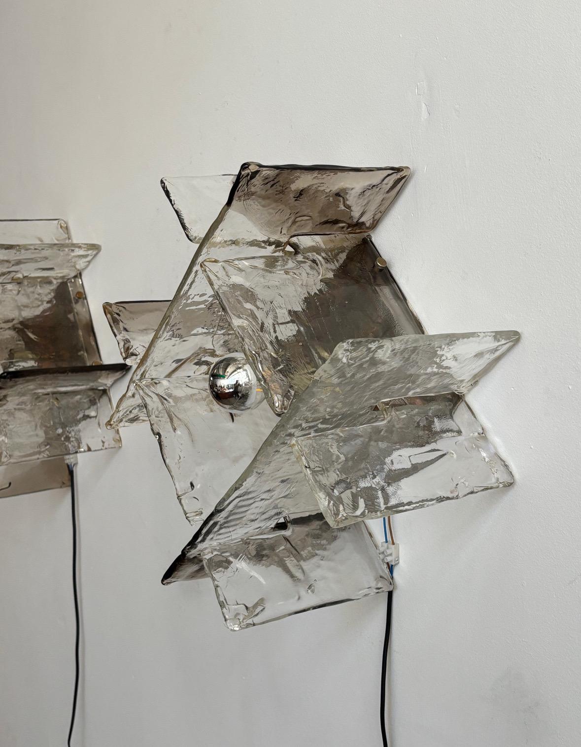 This extraordinary pair of square sconces, designed by Carlo Nason for Mazzega in the 1970s, exemplifies the elegance and craftsmanship of Italian Mid-Century Modern design. Each sconce features a polished steel central structure that supports the