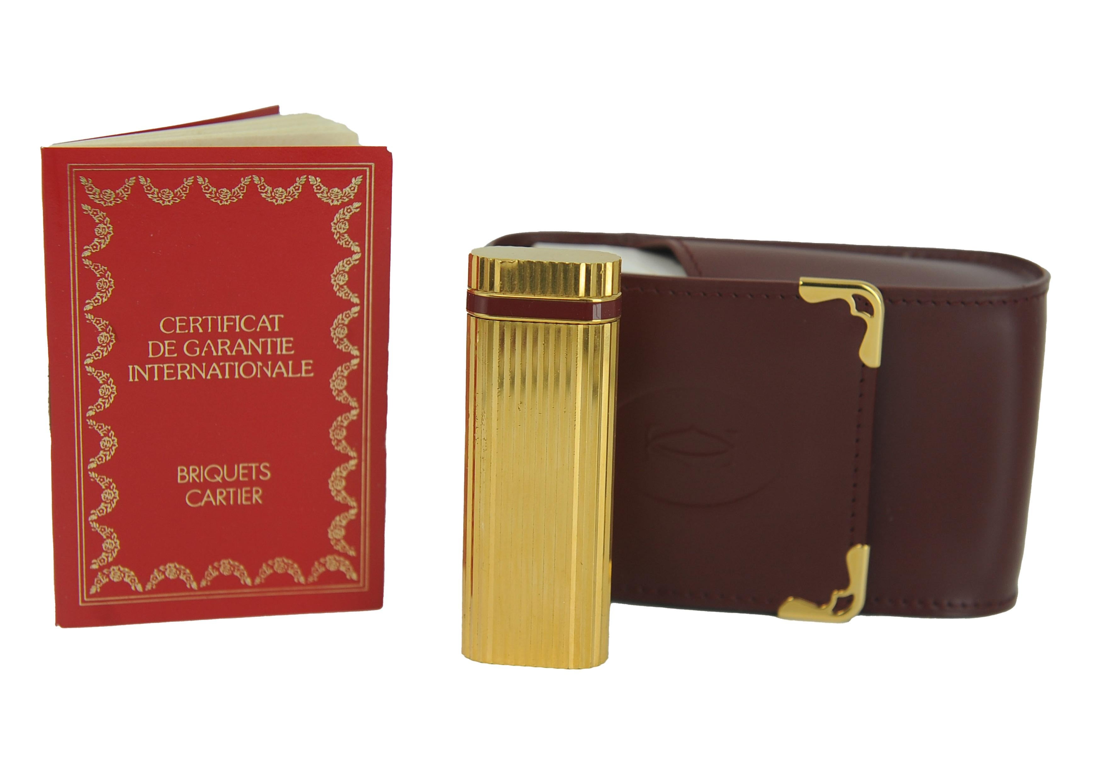 Un raro accendino Godron di Cartier placcato in oro 18 ct con fascia laccata rossa.
Venduto con un portasigarette Cartier in pelle, con garanzia originale
Circa anni '80, Made in Paris, Francia. 
Marcato Cartier Paris alla base dell'accendino 



