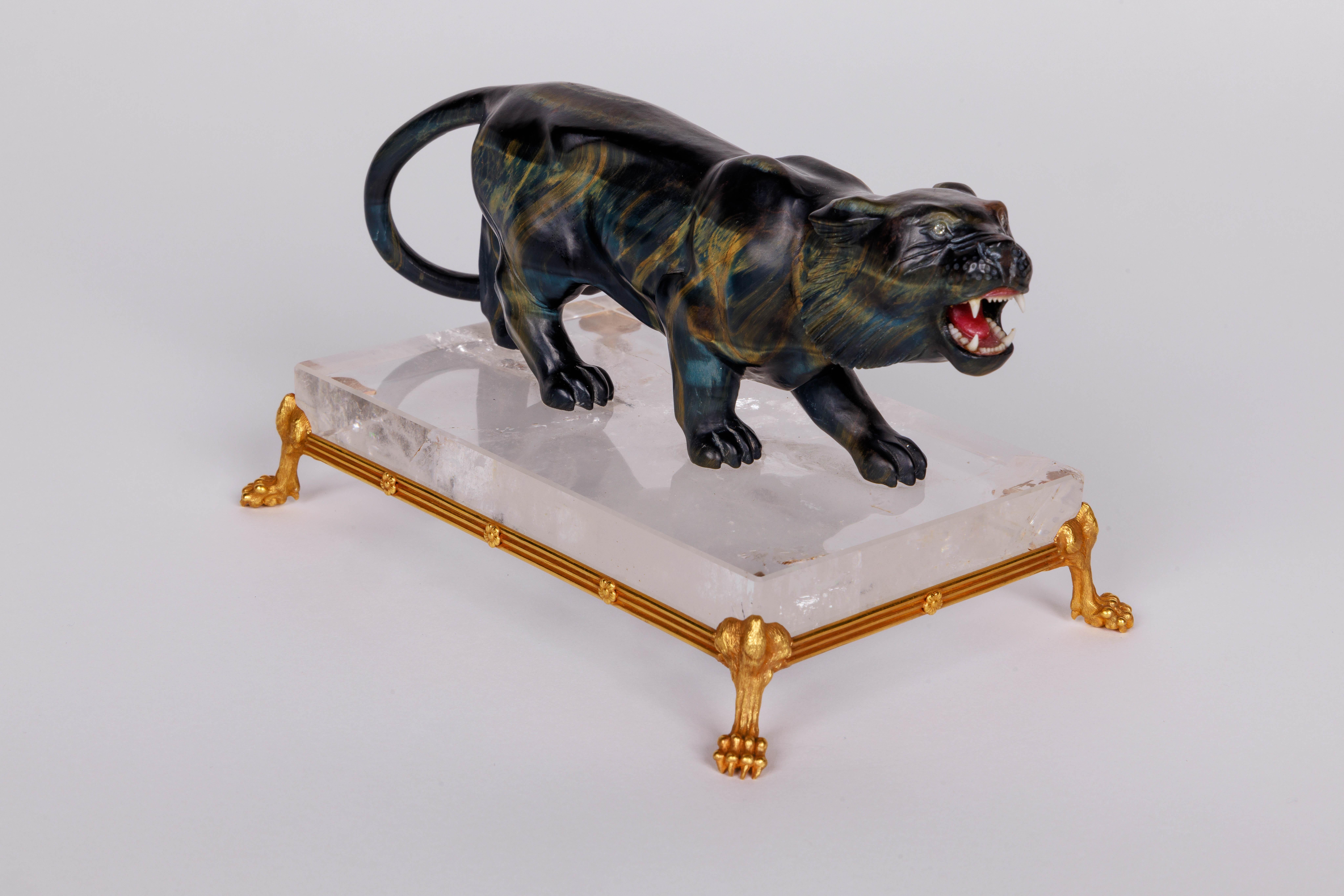A rare carved Hawk's Eye agate tiger on a 14k gold mounted rock crystal base, circa 1960.


