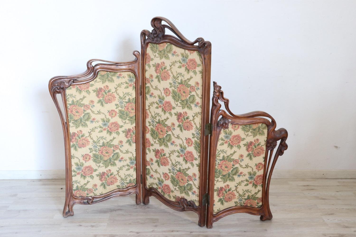 Very rare and beautiful Italian Art Nouveau screen in walnut. The wood is carved with a fantastic wavy line typical of art nouveau decoration. Of remarkable refinement and elegance, equipped with three panels with a fabric decorated with floral