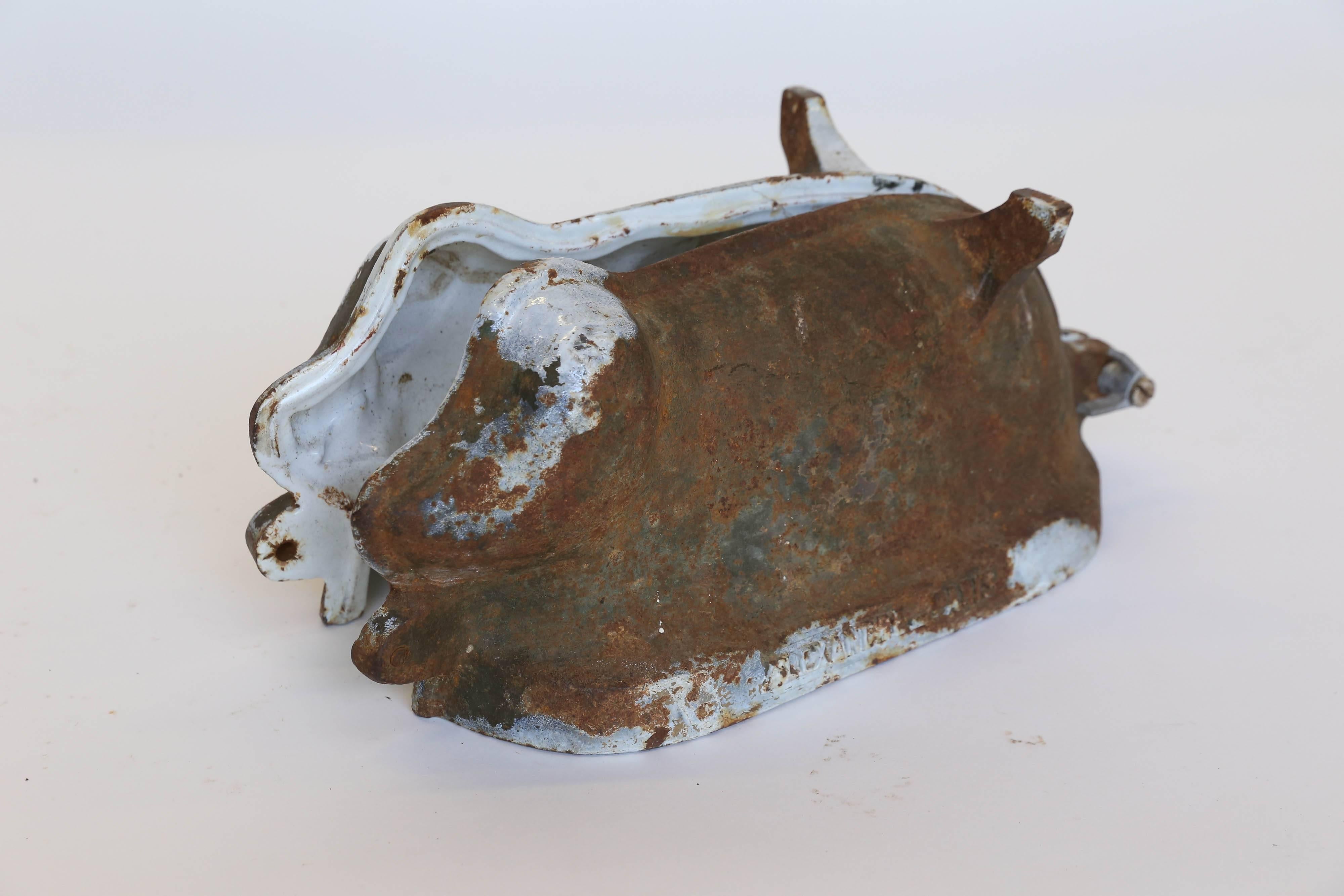 Found in France, a rare cast iron mold in the shape of a pig. The original baked-on white enamel finish is almost completely gone from the exterior surface but is largely intact inside. The two halves were originally held together by large bolts