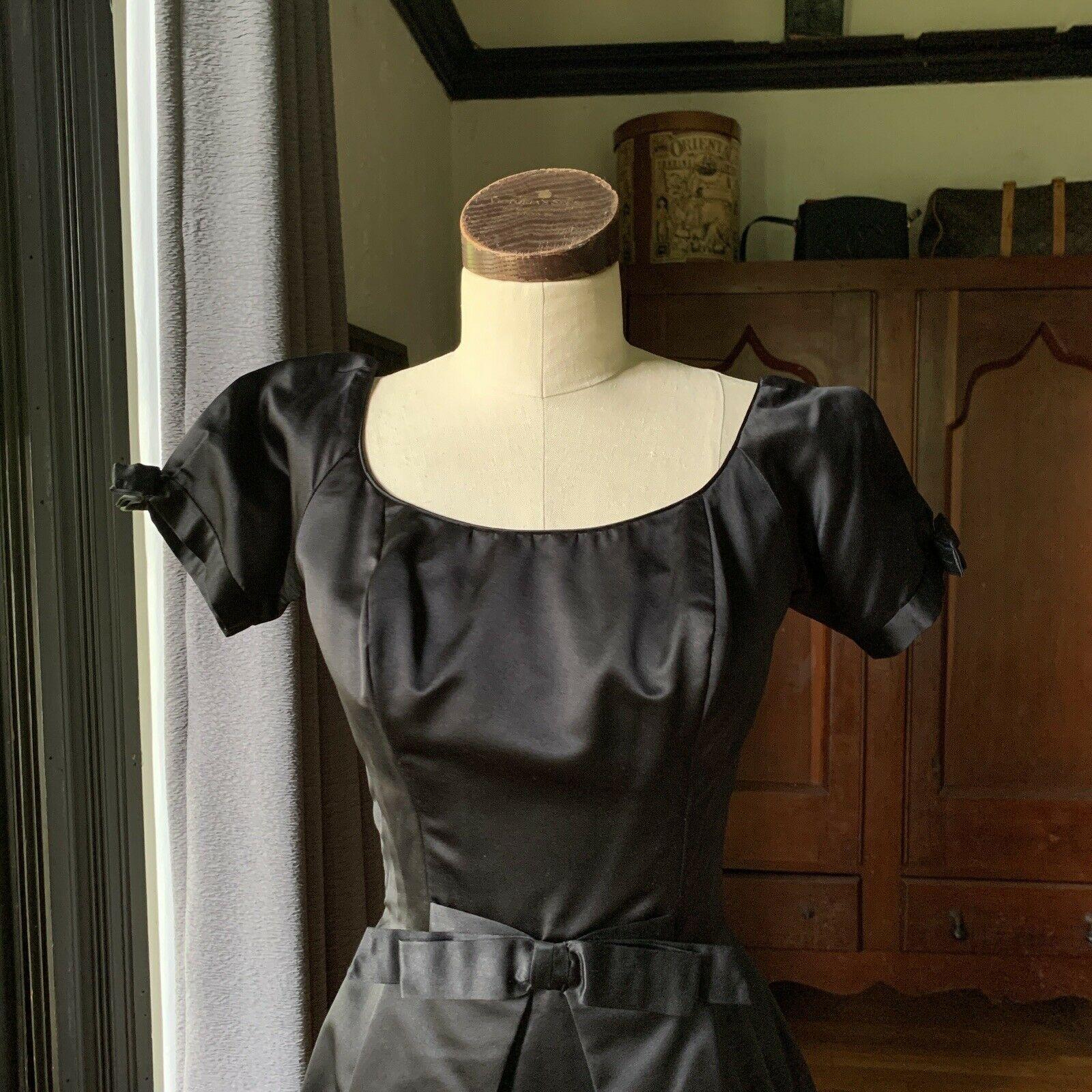 Ceil Chapman, 1950's Era, Pleated Front and Back Panels, Front Bow, Open Top Puff Sleeves with Bows on Ends, Round Neck, Bone In Front and Sides, Back Zipper, Hook and Eye Black Closure, Iconic Chapman Label Intact, Gorgeous Black Satin, Size