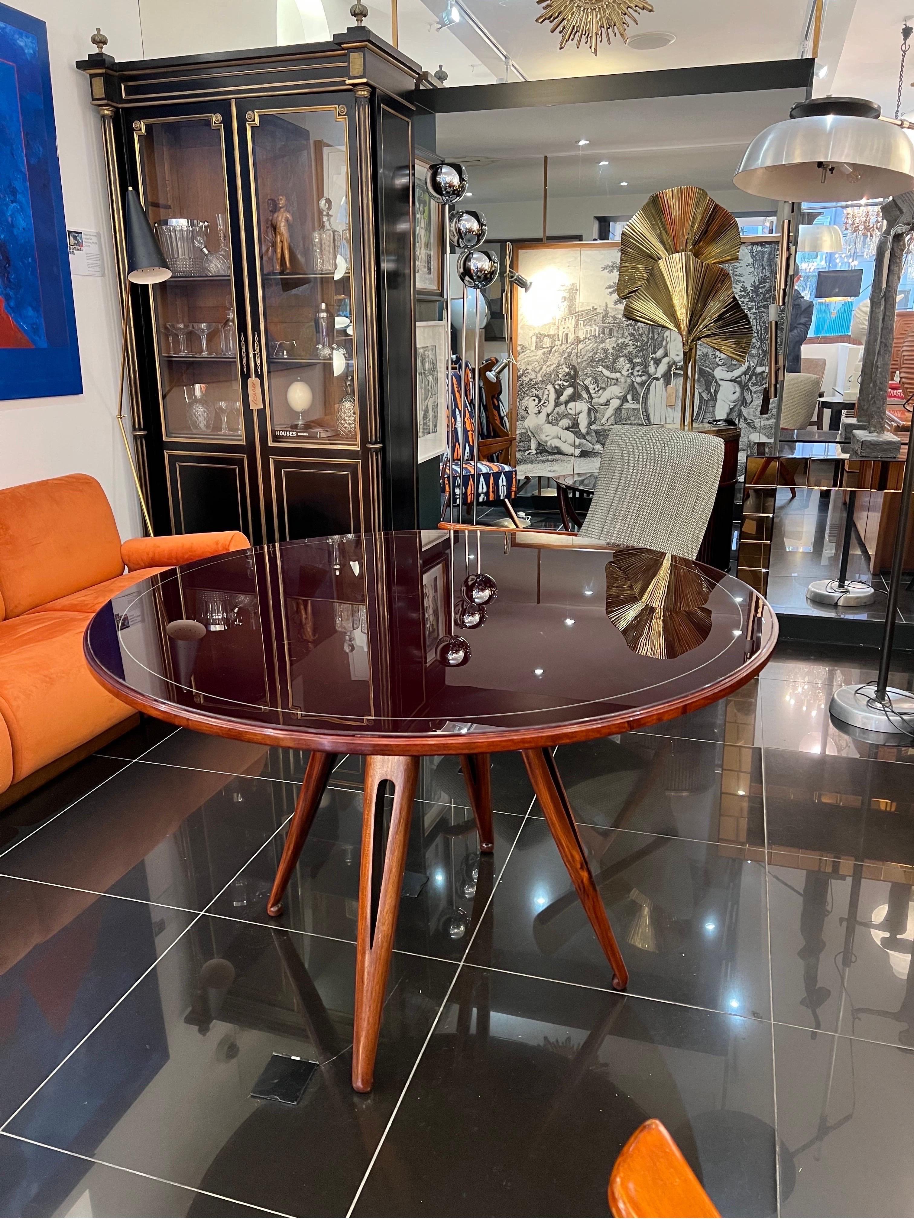 An elegant centre or dining table in solid walnut wood designed by Silvio Cavatorta in the 1950s. The table top bares its original mulberry glass top that slots directly into a framed base and the beautifully designed legs support the table from the