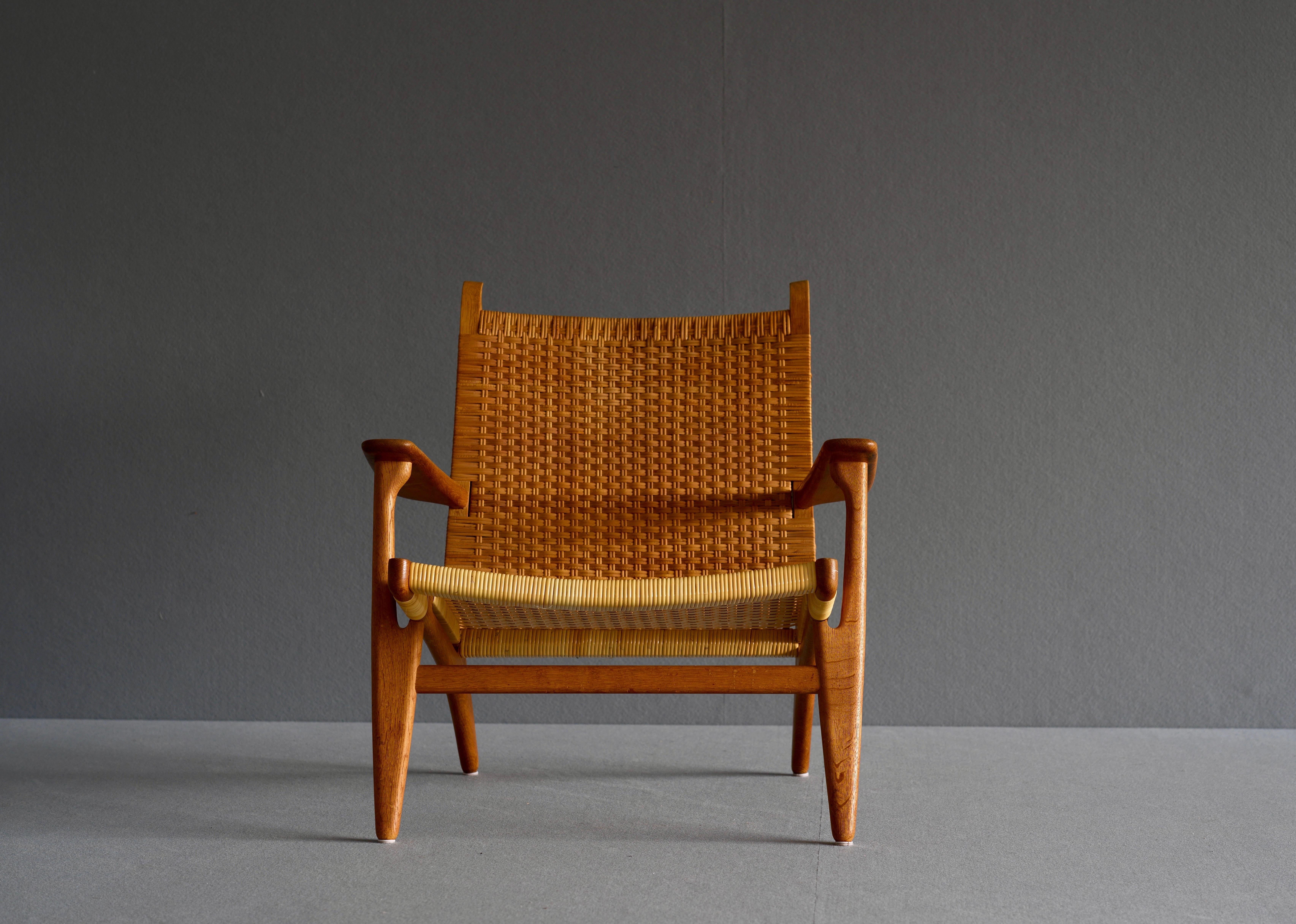 Lounge chair by Hans Wegner for Carl Hansen. it is in solid oak with the seta and back fitted with woven cane. This stunning lounge chair was designed in the 1950’s and represents a highlight in Wegner’s production. It went out of production in the