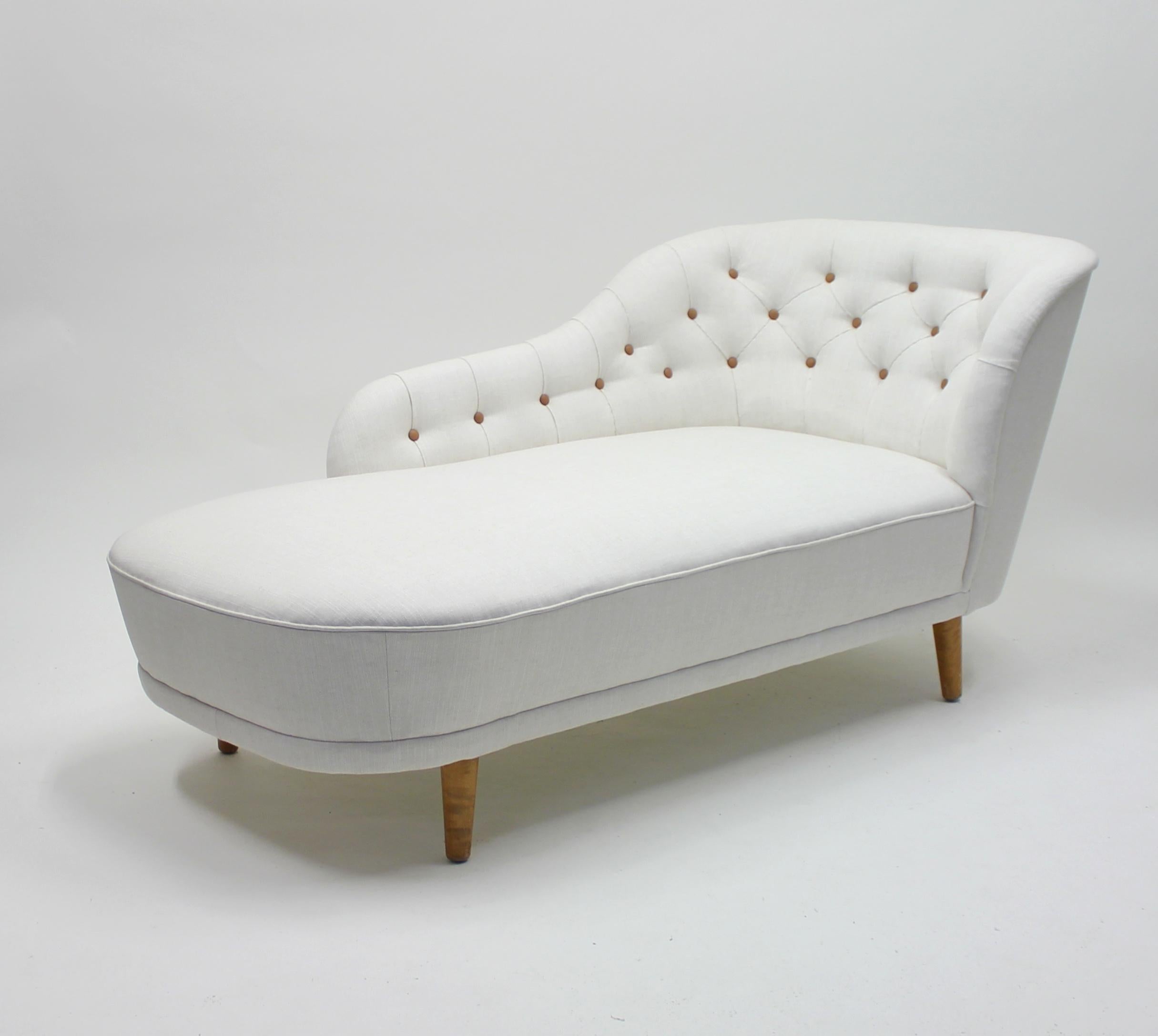 Rare chaise lounge, attributed to Swedish designer Greta Magnsusson Grossman for her own firm Studio. Made in the 1940s. New white linen upholstery with brown leather buttons in the backrest. Stained birch legs. Very good condition with new padding