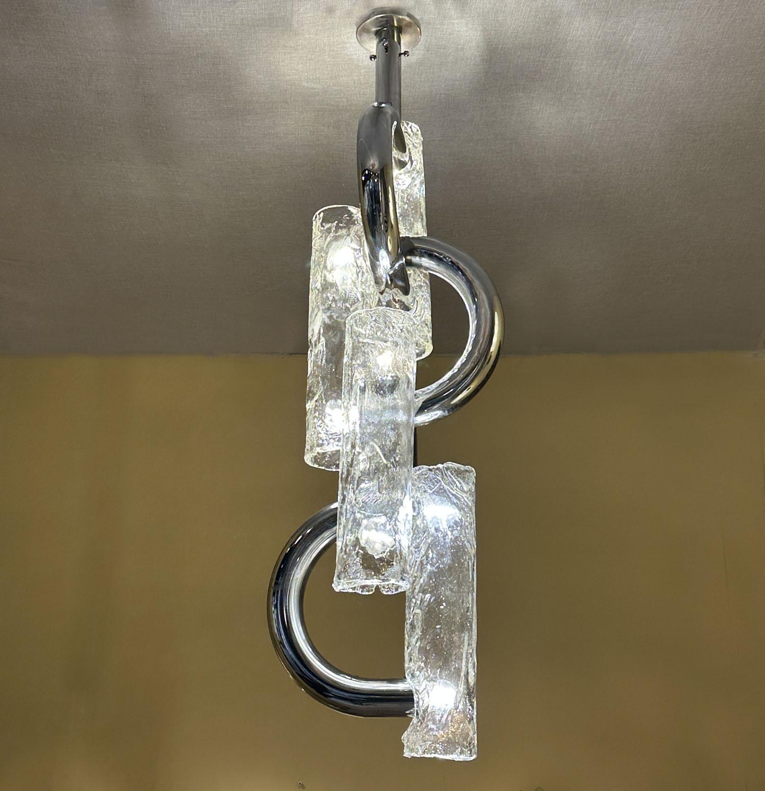 Very rare Mid-Century Modern elongated chandelier or pendant with clear Murano glass and chrome segments by Aldo Nason for the manufacture Mazzega, , Italy ca.1970. The chandelier is constructed by U shape tubular chrome structure with four large