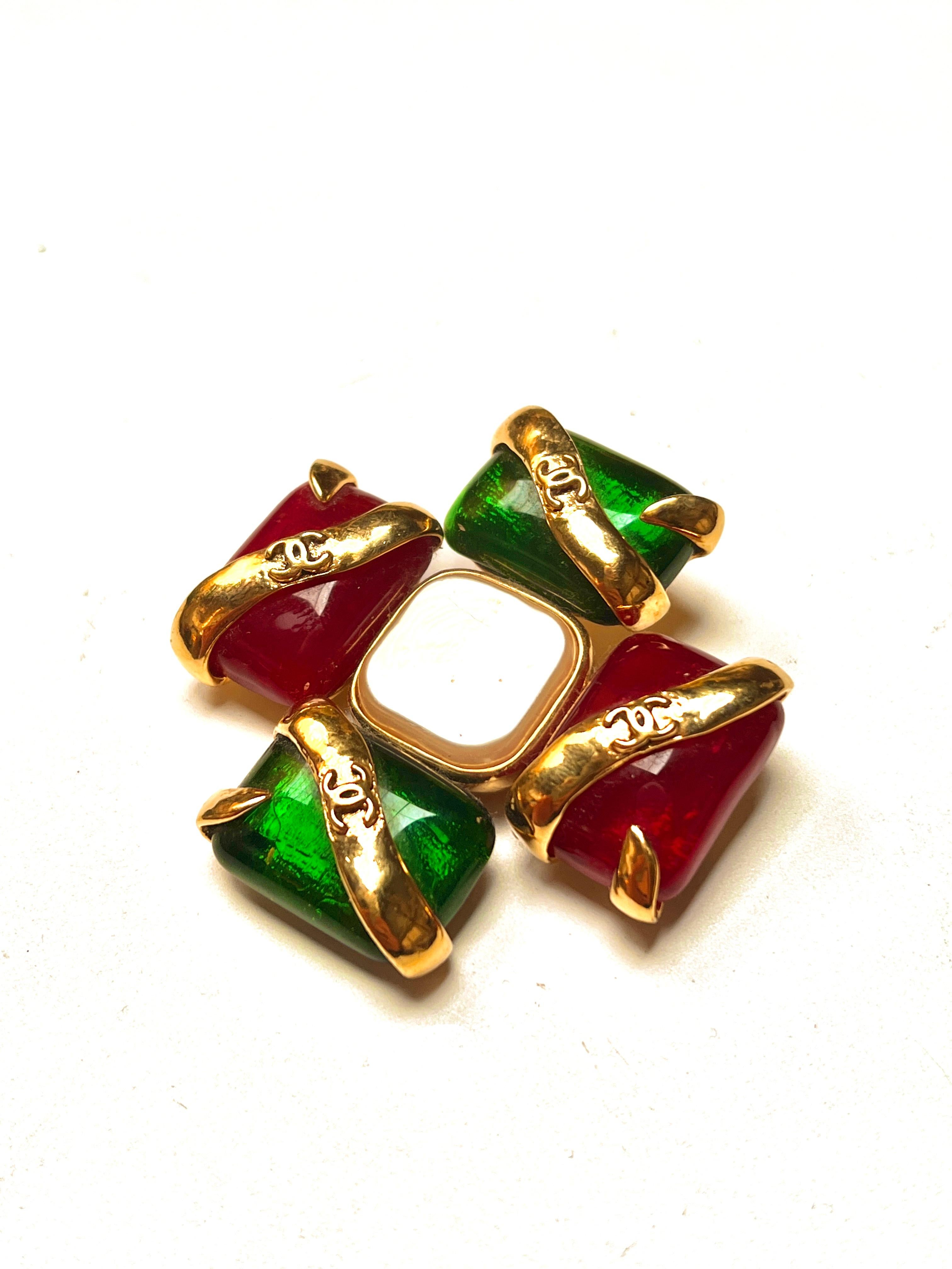 A beautiful early signed and dated Chanel brooch from the 1990s made by Robert Goossens Paris.  The beautiful green and red glass stones from the House of Gripoix, centered around one large Faux-pearl. The stones are wrapped in gold colored bands
