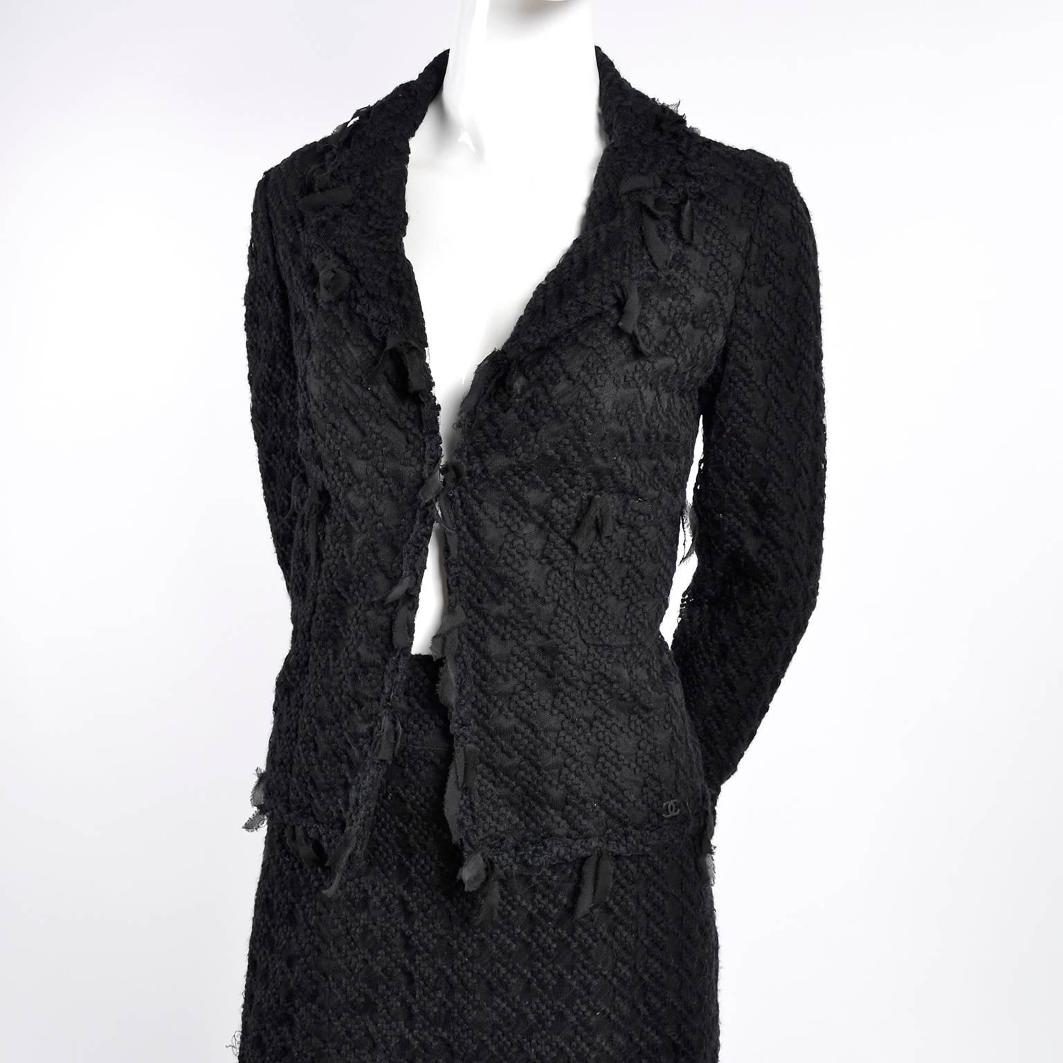 This is a highly desirable and coveted 2 piece Chanel skirt suit with fine embroidered mesh overlay over black wool tweed and ribbon trim. The jacket is labeled a size 40 and is lined in black silk. The jacket has the Chanel camellia buttons at the
