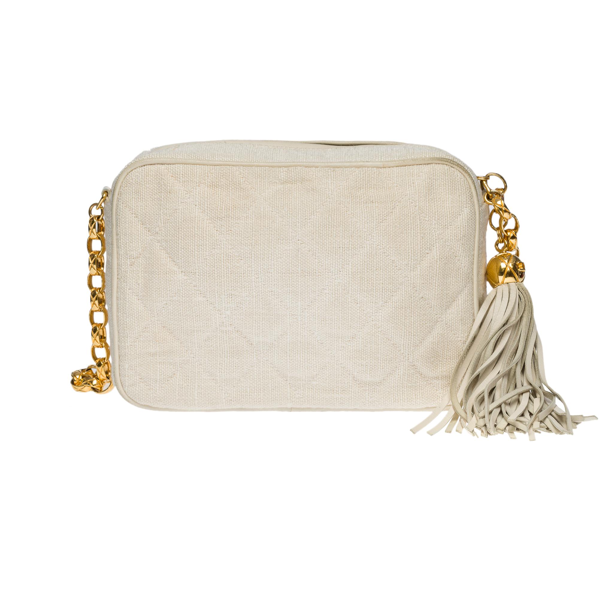 Rare Chanel Mini Camera shoulder bag in ecru quilted linen, gold-plated metal hardware, a gold-plated metal chain handle for hand, shoulder or crossbody support
2 stacked patch pockets on the front
Gold charm on the zip with white leather fringe
A