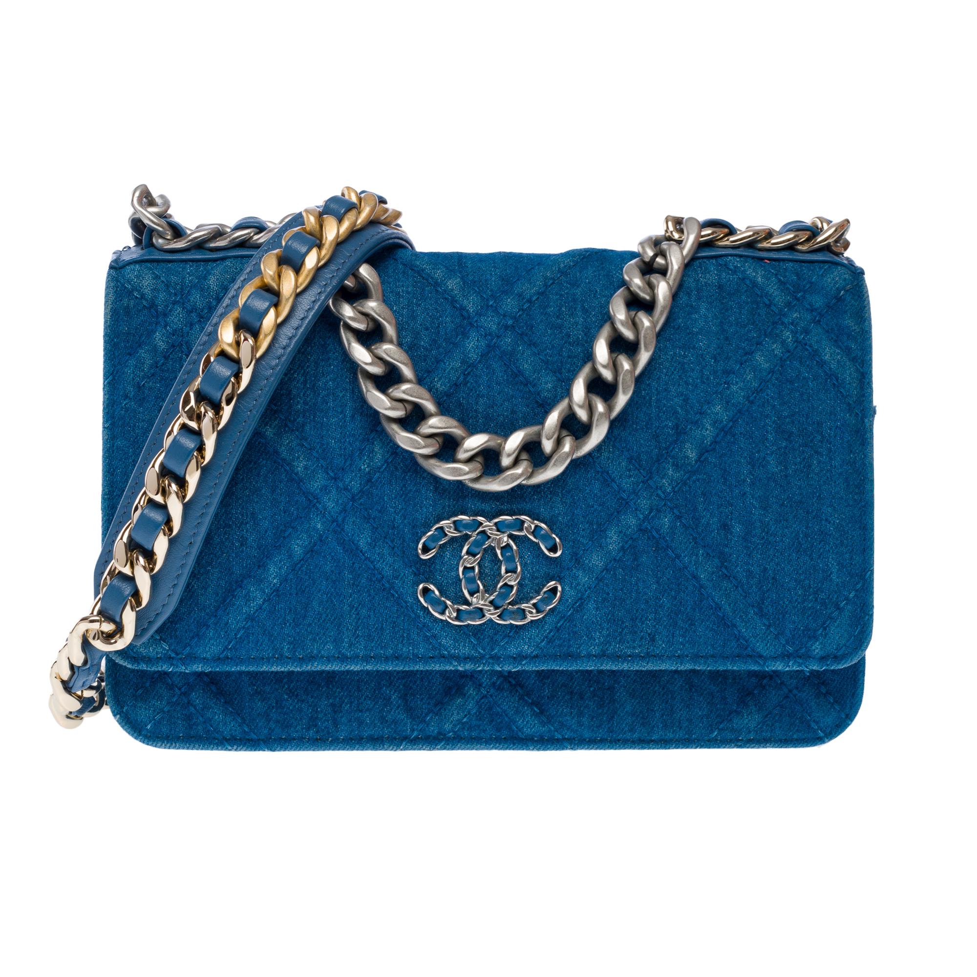 Stunning​ ​Chanel​ ​Wallet​ ​On​ ​Chain​ ​(WOC)​ ​19​ ​shoulder​ ​bag​ ​in​ ​blue​ ​denim,​ ​with​ ​matte​ ​silver​ ​metal​ ​trim,​ ​a​ ​matte​ ​silver​ ​metal​ ​handle,​ ​an​ ​interlaced​ ​matte​ ​silver​ ​and​ ​gold​ ​metal​ ​chain​ ​strap​