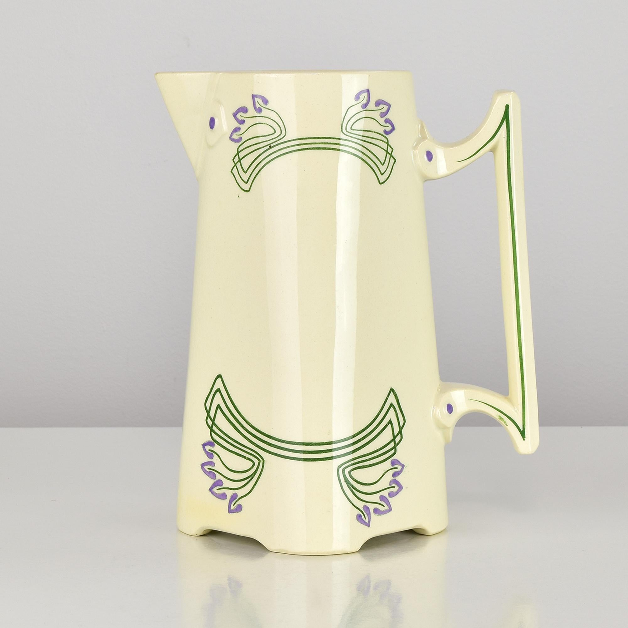 Una rara e affascinante brocca per cioccolata o acqua in stile Art Nouveau, realizzata da Sarreguemines in Francia intorno al 1900. Questo elegante pezzo mette in mostra l'estetica raffinata dell'epoca Art Nouveau, con il suo corpo angolare, il