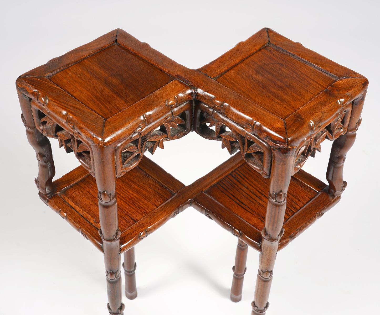 This rarely seen Chinese Hung Mu wood two top stand or table, dating to the late 19th century, features two joined square panel tops above carved open work friezes and a lower similar tier resting on legs carved in the style of bamboo small sprigs.