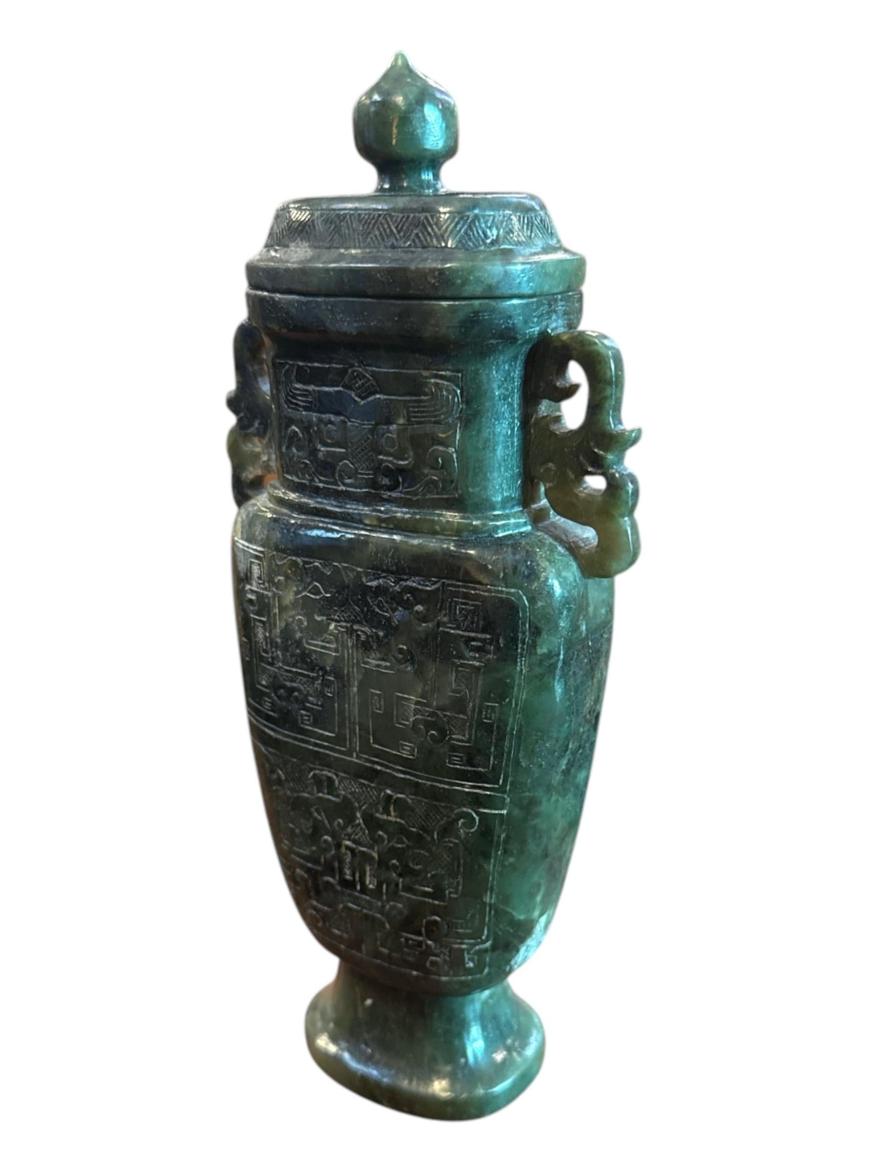 Este exquisito jarrón chino de jade verde tallado a mano es un verdadero testimonio del arte y la artesanía de los antiguos escultores de jade. Tallado en una sola pieza de auténtico jade verde, este jarrón encarna la gracia, el refinamiento y el