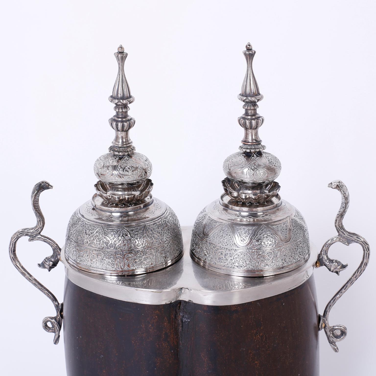 Rare coco de mer tea caddy crafted with the unusual double lobe nut found on the Seychelles Islands and it is said to have mystical properties. Featuring hand-hammered silver metal lids, cobra snake handles, and an octagon base on a round ebony