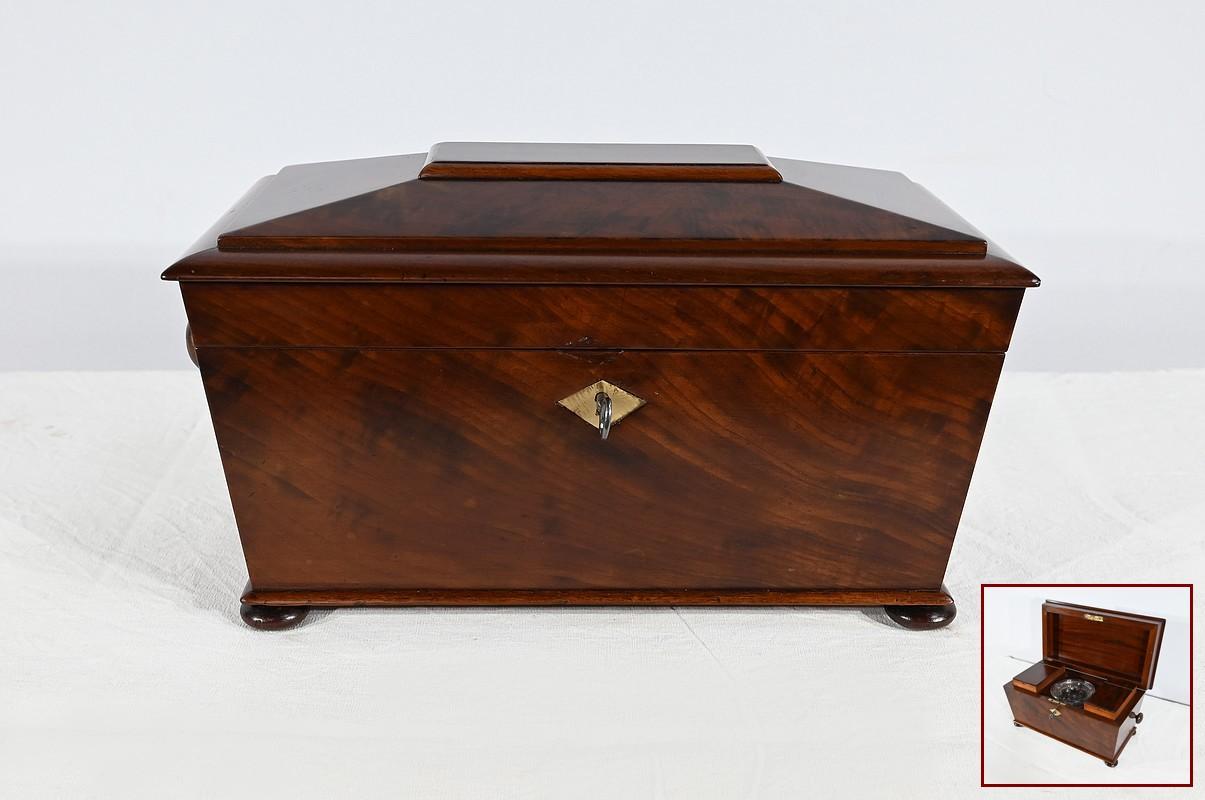 Un antico baule da tè, un bene prezioso all'inizio dell'epoca vittoriana. Questa scatola di mogano chiusa a chiave conservava le foglie di tè e veniva esposta nei salotti degli aristocratici inglesi. Questo esempio presenta due scomparti sui lati