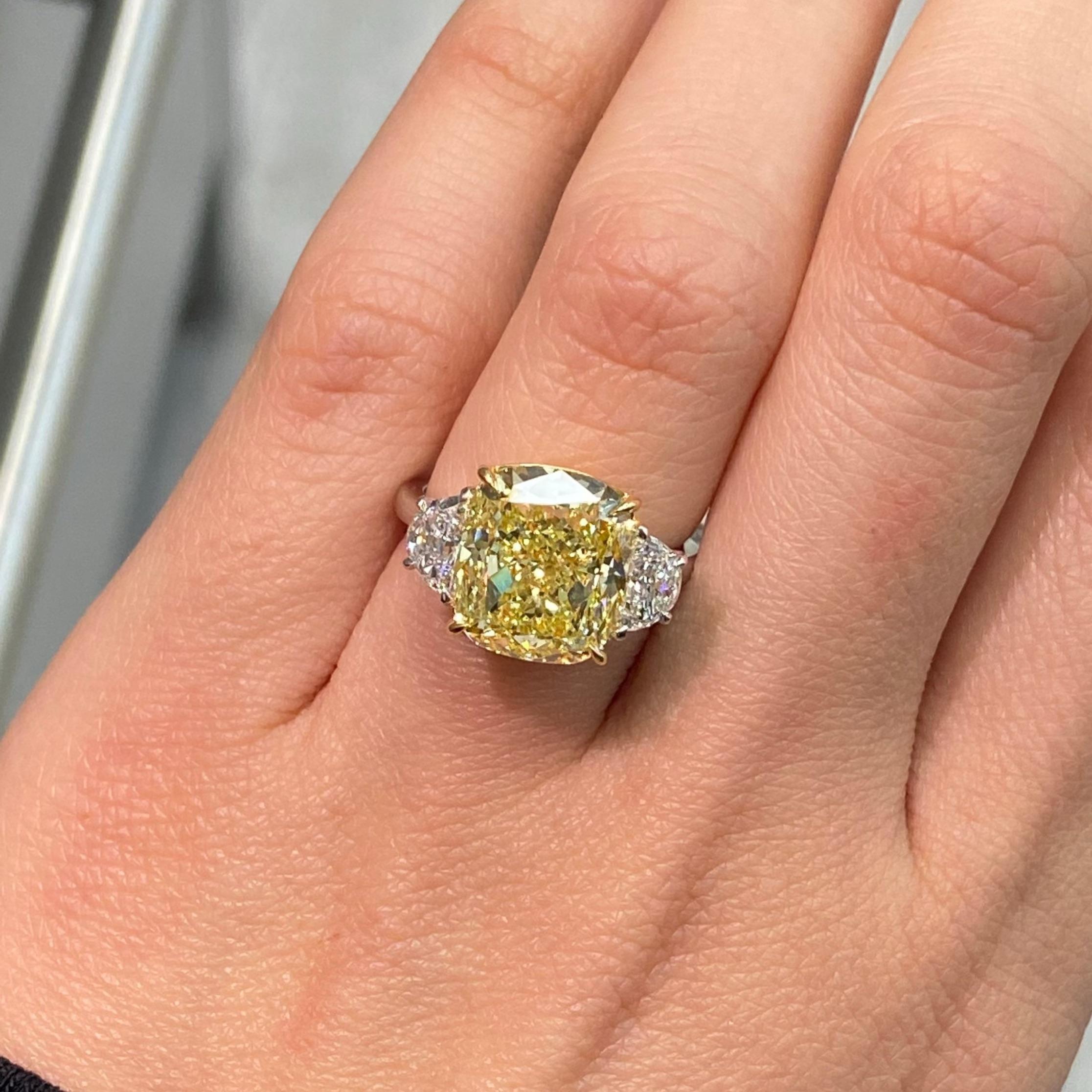 Celebrate love’s brilliance with this stunning three-stone engagement ring, handcrafted in New York City to perfection. At its heart lies a breathtaking 7.07-carat Fancy Yellow cushion-cut diamond, certified by GIA for its exceptional color and VS2