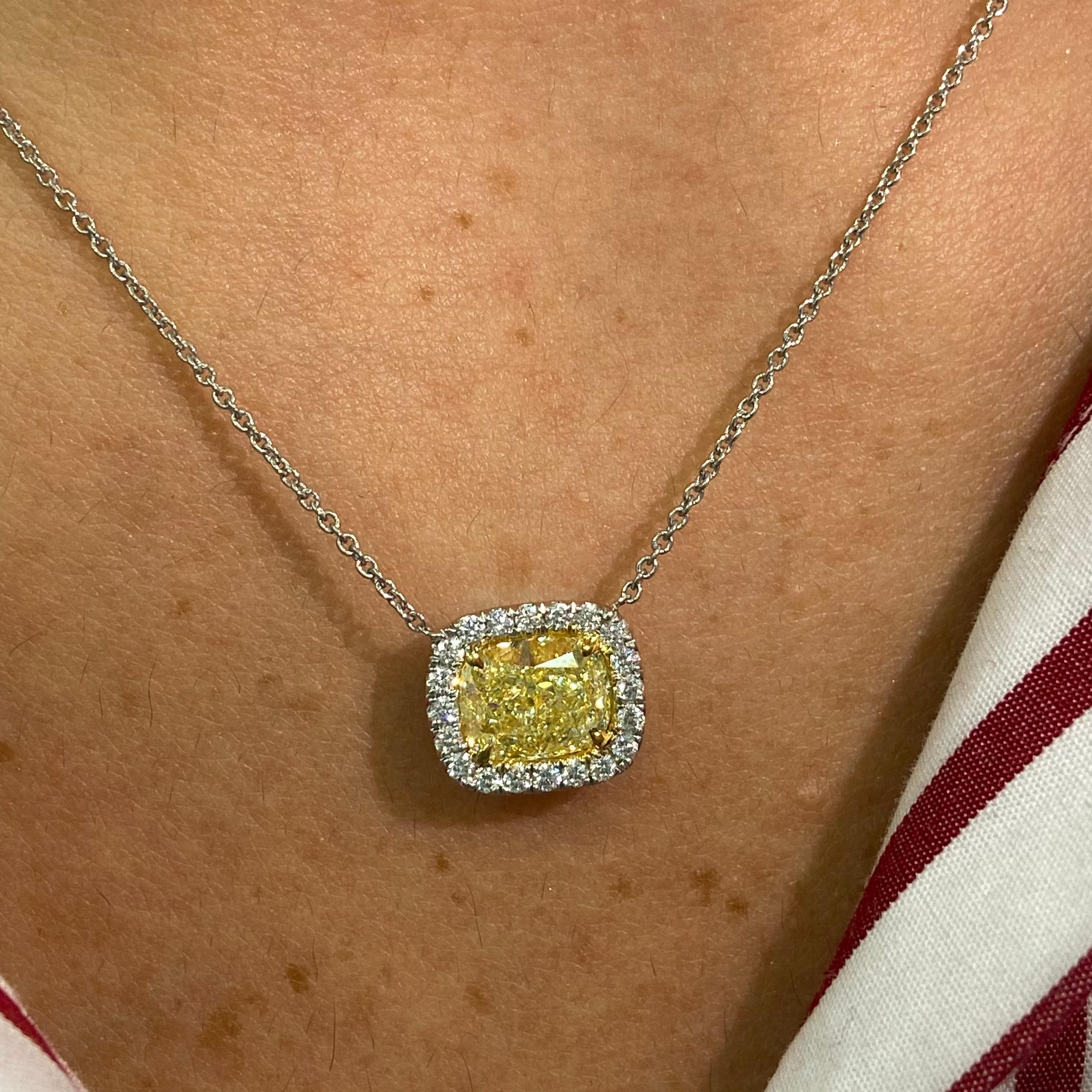 This pendant features a beautiful 2.01-carat fancy light yellow cushion-cut diamond with VVS1 clarity and excellent cutting for a soft, natural glow. Framed by 0.24 carats of white diamonds, the halo adds a touch of brightness that enhances the
