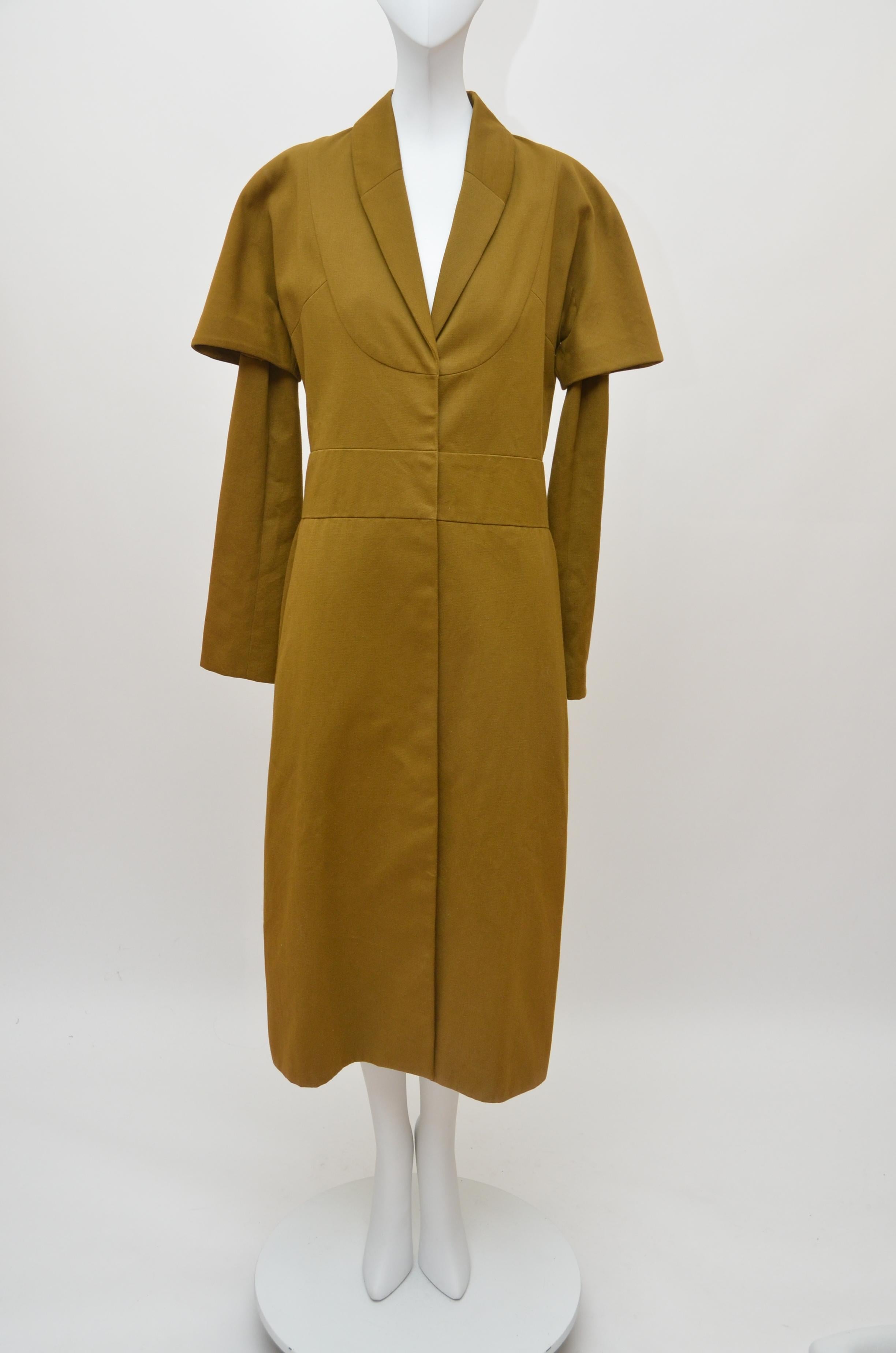A rare and early Comme des Garçons 'Obi' coat, probably late 1970s, with unusual blue on ivory woven satin label, of heavy cotton, lined in polyester crêpe, with curved front 'bib' panel, under and over sleeves, the waistband applied to the rear