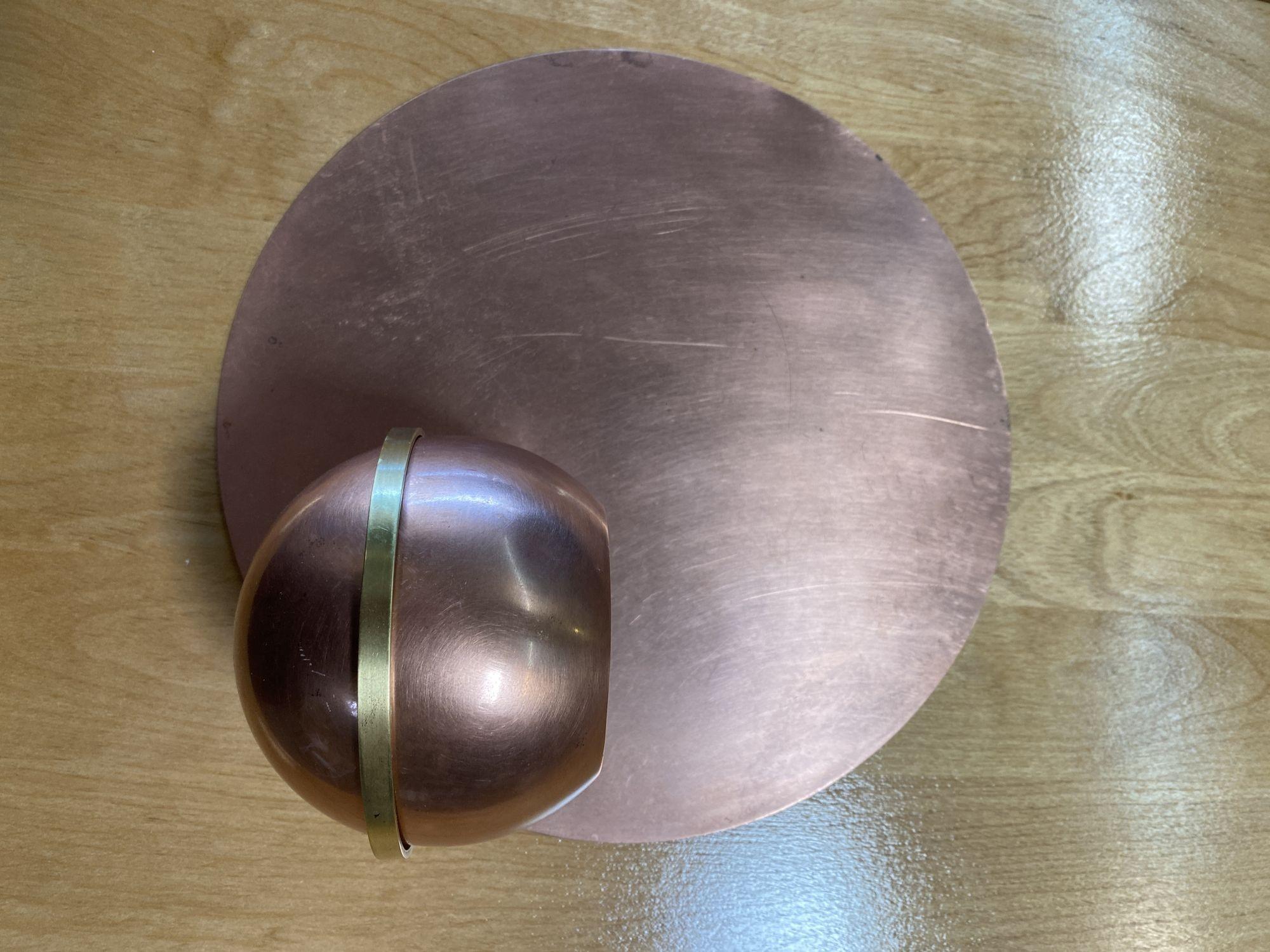 Rare matching pair of copper and brass Art Deco wall planter set by Chase Brass featuring 2 wall platters each a mirror image of the other with a round copper backplate, brass ring-shaped holder, and removable sphere-shaped planter.