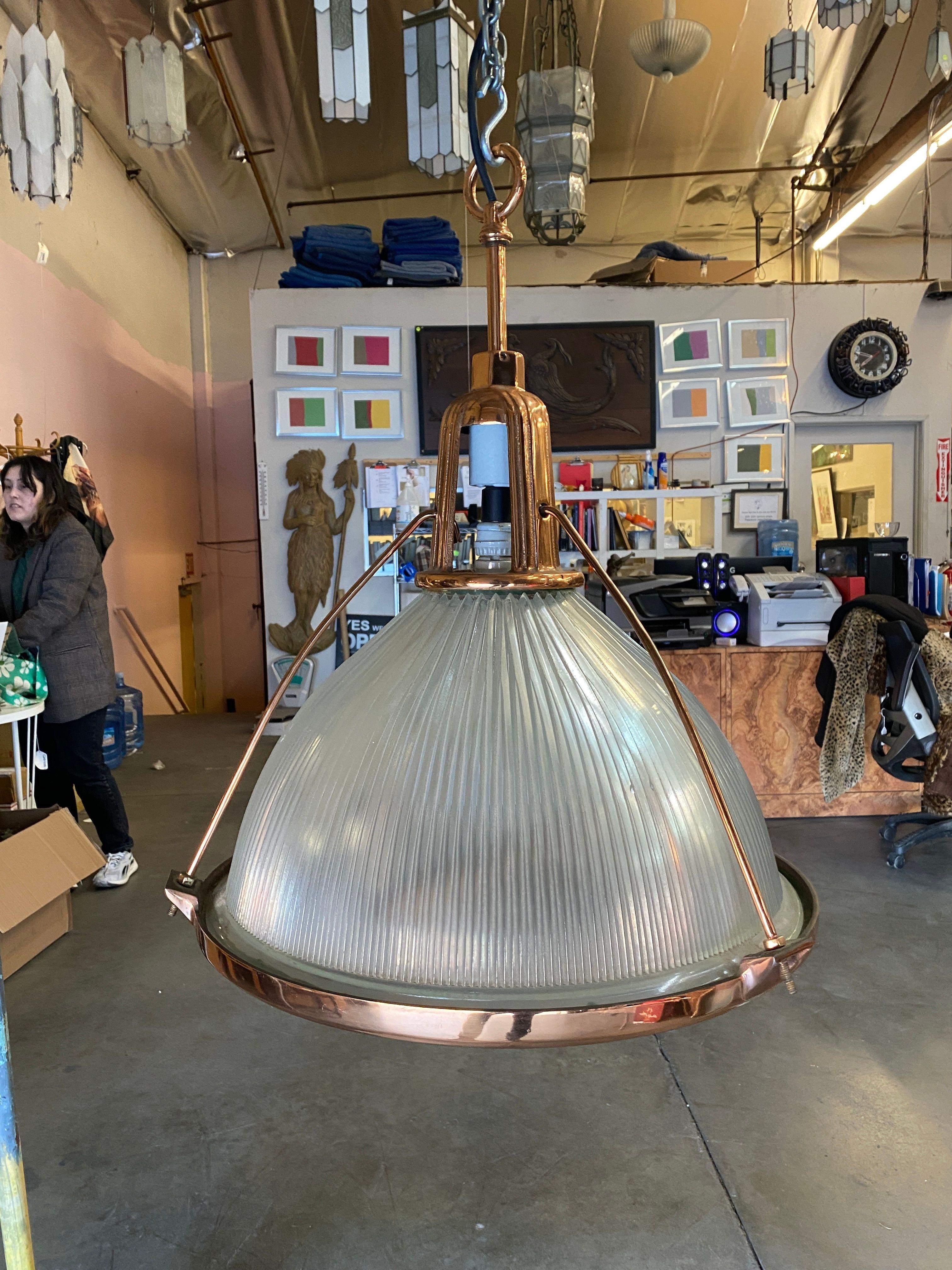 This industrial yet elegant hanging lamp from the 1940s features a Holophane glass shade. These pendant lights are connected by an aluminum casing fixed to the top of the light fixture and are a rare copper plated variant not seen often.

A