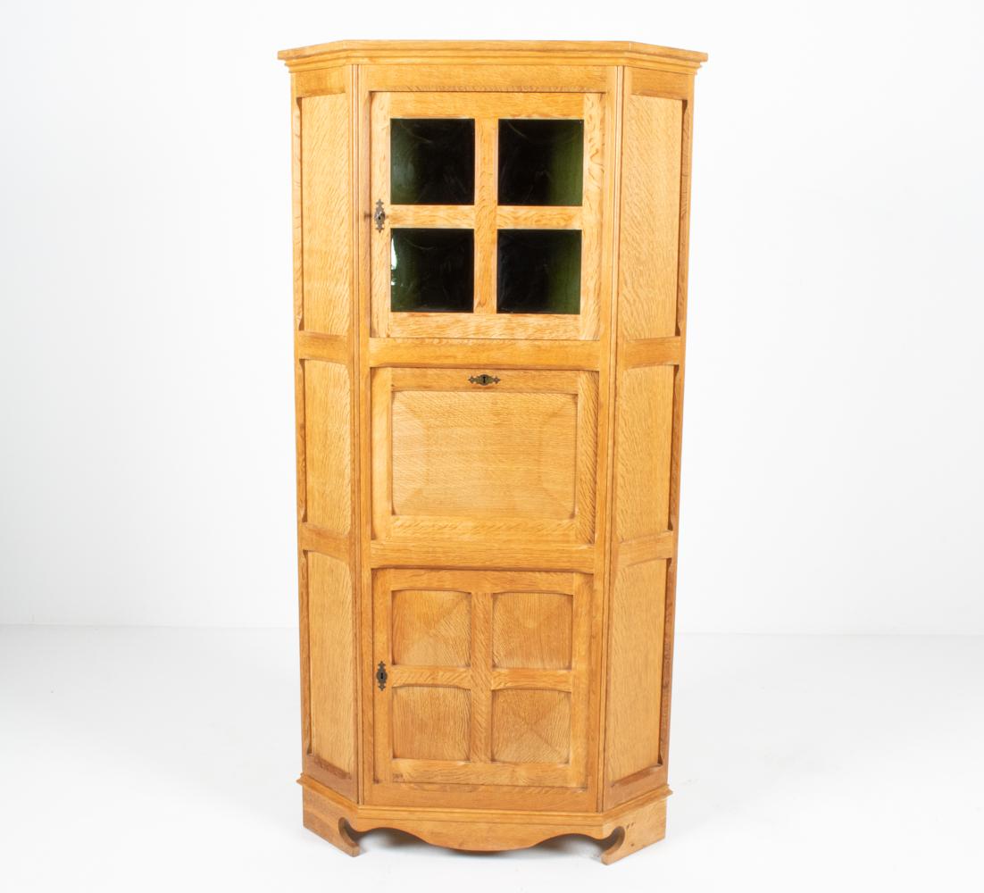 Traditional Craftsman details take center stage in this fabulous and rare corner cabinet by Henning Kjærnulf; from the front door - adorned with convex stained glass panels of rich bottle green (harkening back to Edwardian bubble glass) - to the