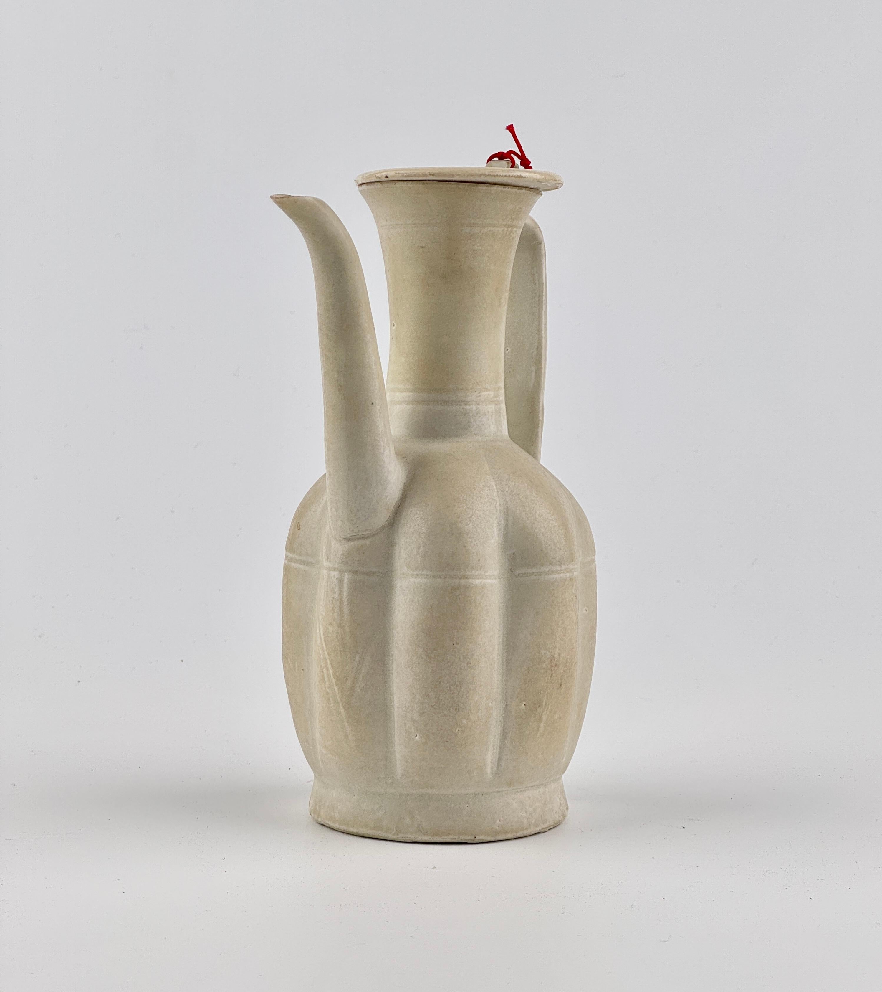 This is a Song Dynasty ceramic ewer, exhibiting the characteristic simplicity and elegance of the period. The ewer's form is sturdy with a full-bodied base that tapers gently to a narrow neck, expanding again at the mouth. The handle is gracefully
