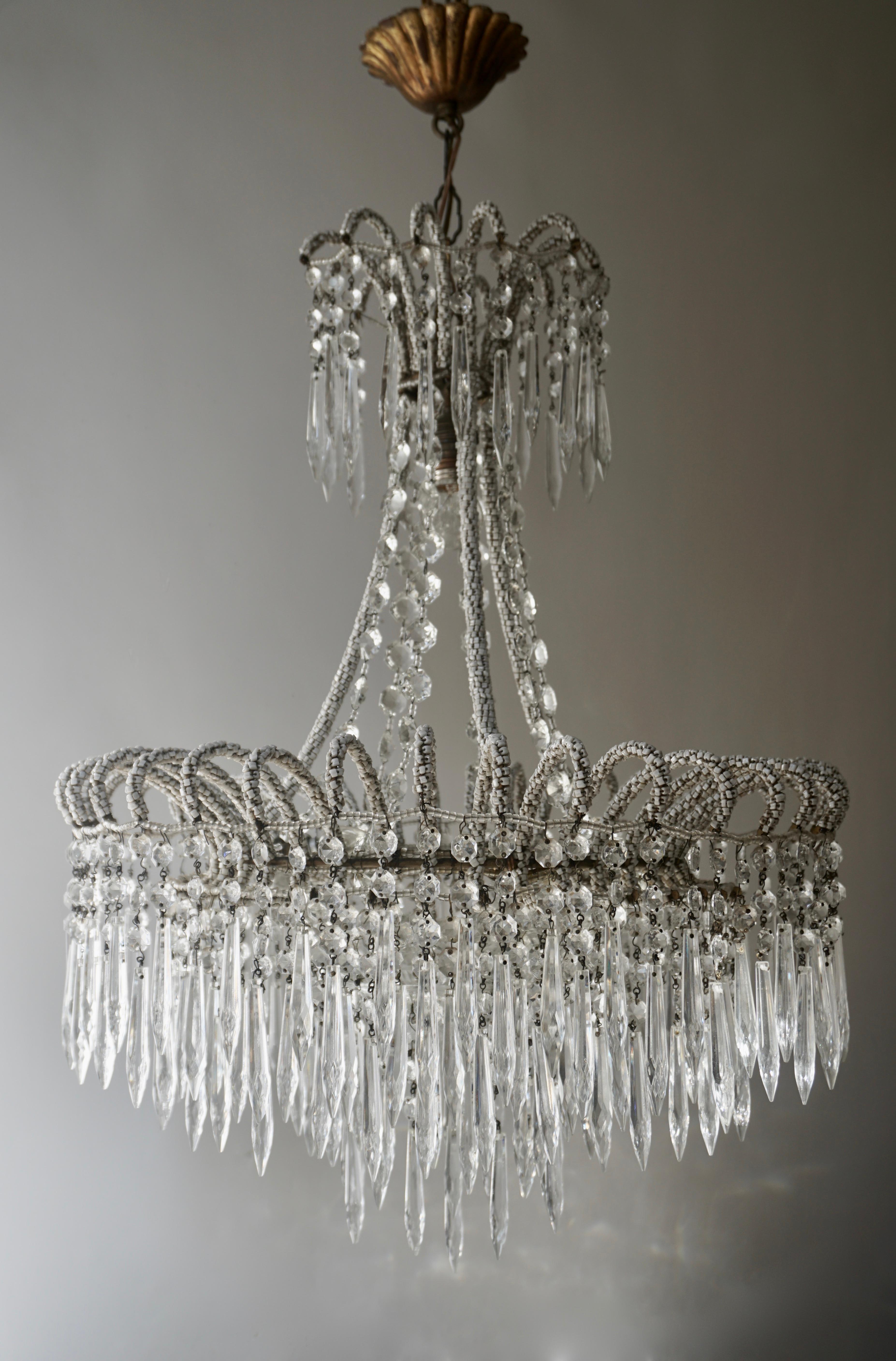 A crystal Victorian style waterfall chandelier with a brass frame that is covered with thousands of small white Murano glasses and three concentric rings hung with crystal icicle drops.

The light requires three single E14 and one E27 screw fit