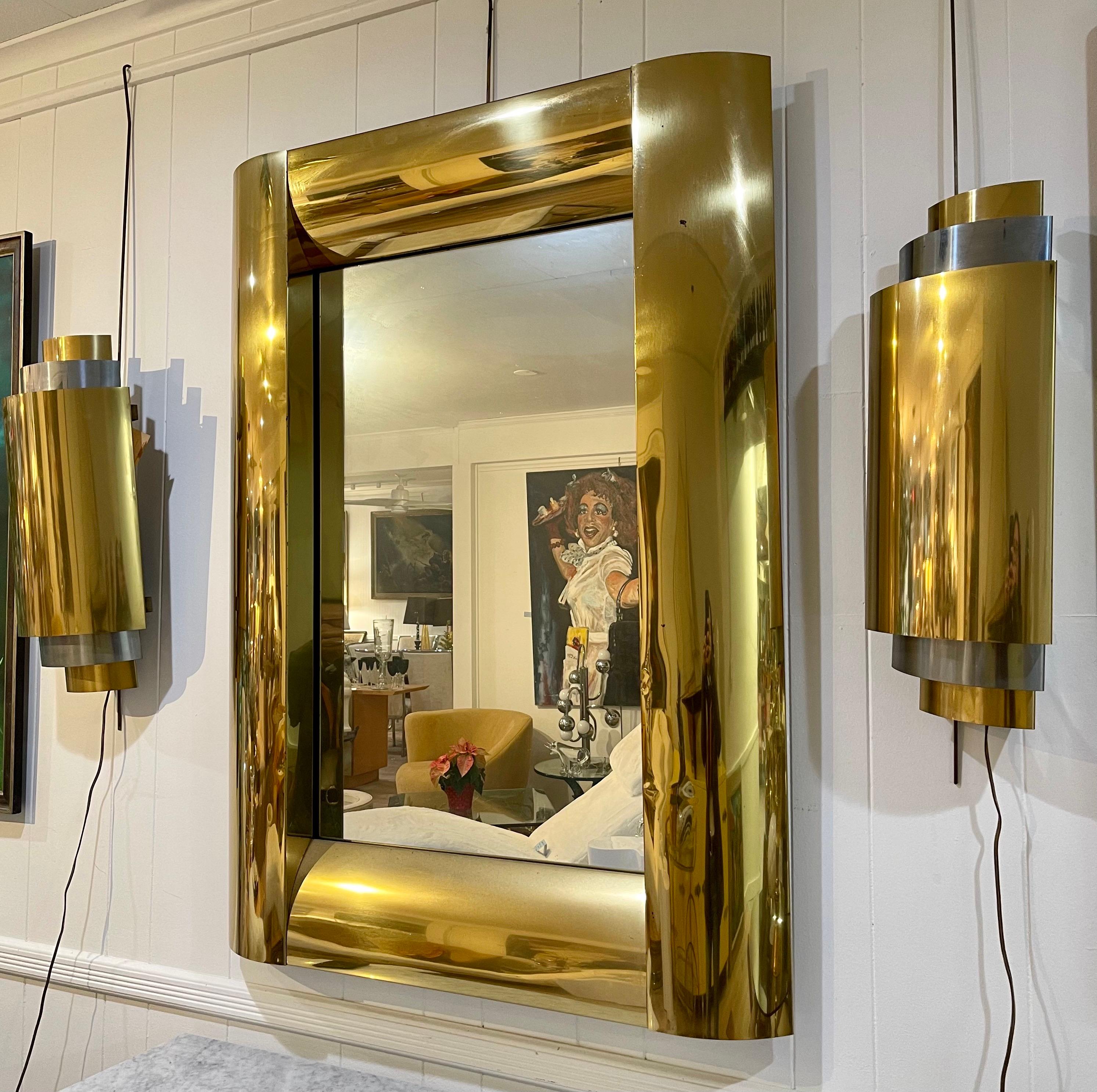A coveted set of wall sconces and wall mirror design in the 1980s by Curtis Jere. The wall sconces were designed in tandem with the mirror by Curtis Jere. The mirror dimensions are below and the sconces, which are electrified measure 7 by 22 inches