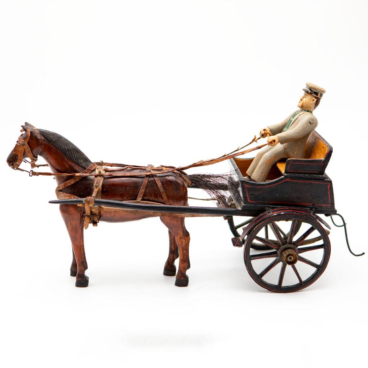 Charmant jouet antique bien conservé en forme de charrette avec cocher et cheval, fabriqué en bois avec un travail artisanal détaillé.

Le chariot est peint en noir avec de fines touches de rouge. Le cocher est vêtu d'un uniforme détaillé avec une
