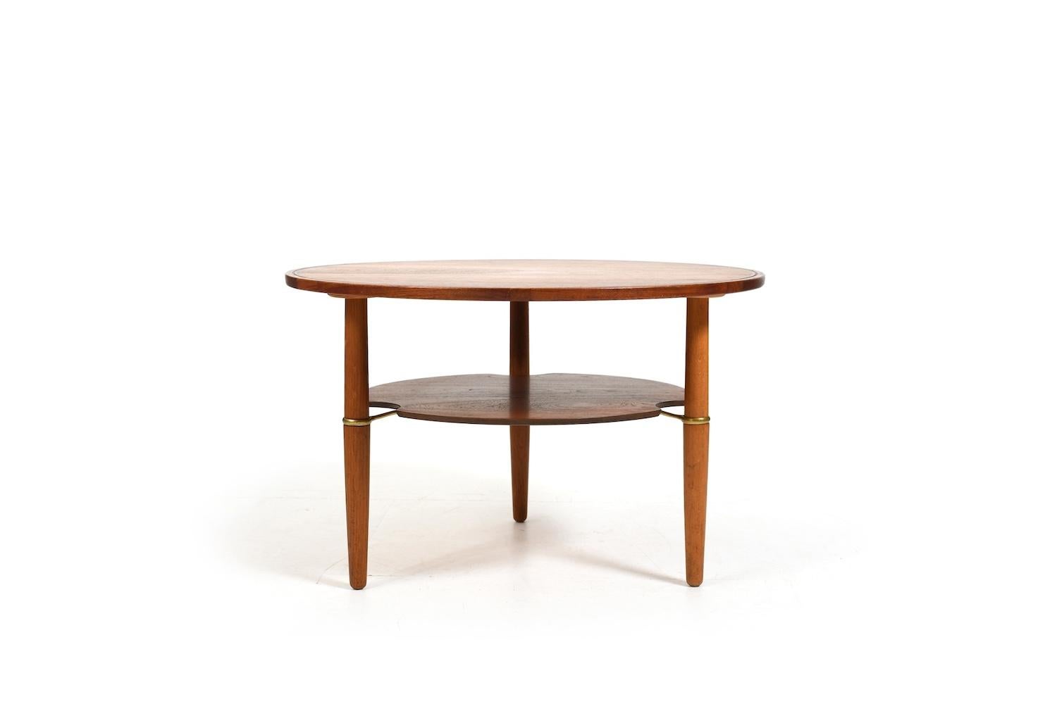 Rare table basse ronde danoise. Fabriqué en teck et en chêne. Sous le plateau de la table se trouve un autre compartiment de rangement maintenu par des supports en laiton. En dessous avec un numéro comme Frits Henningsen travaille. Haute qualité.